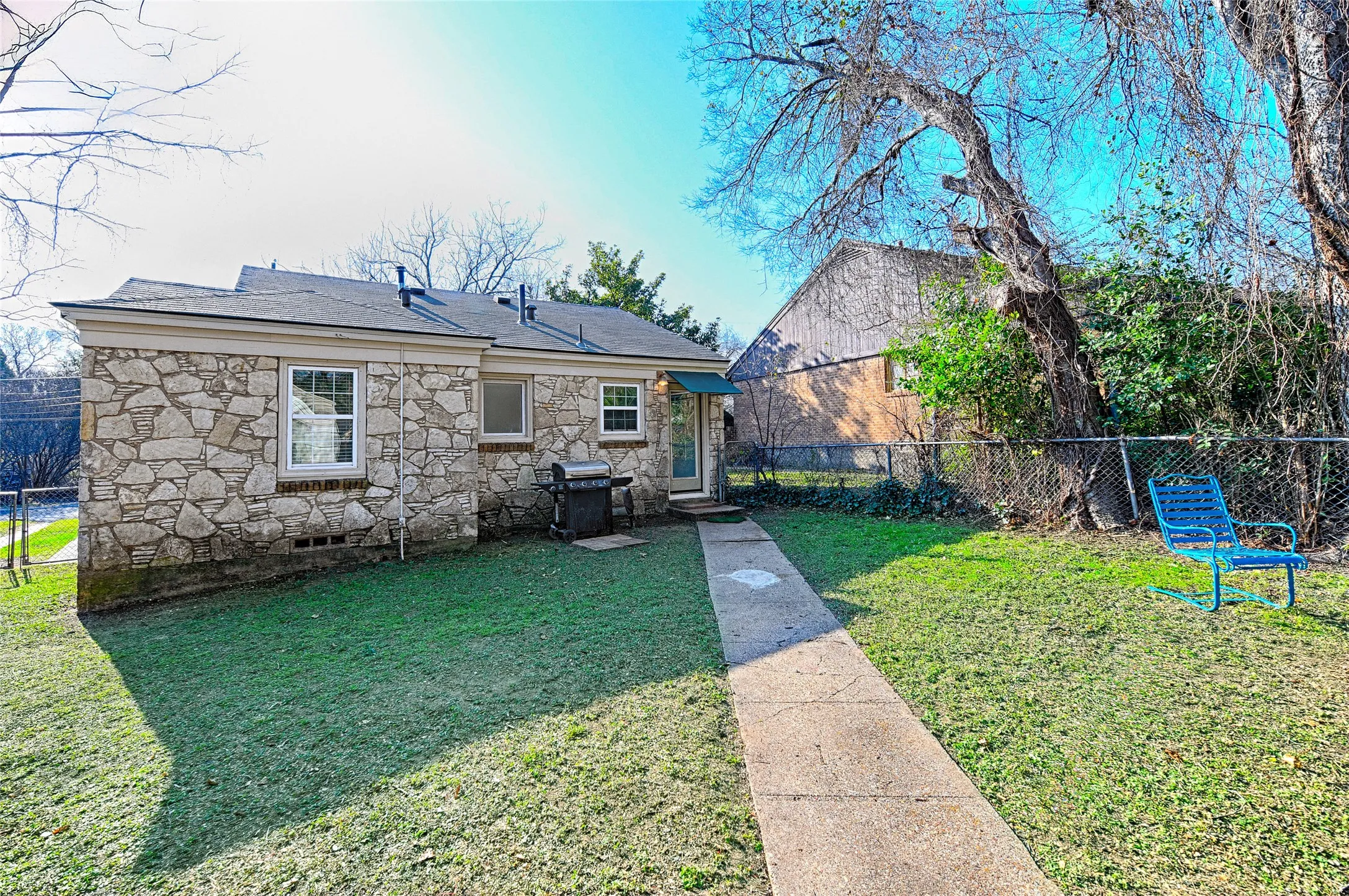 Rear view of house with a fenced backyard with stone siding