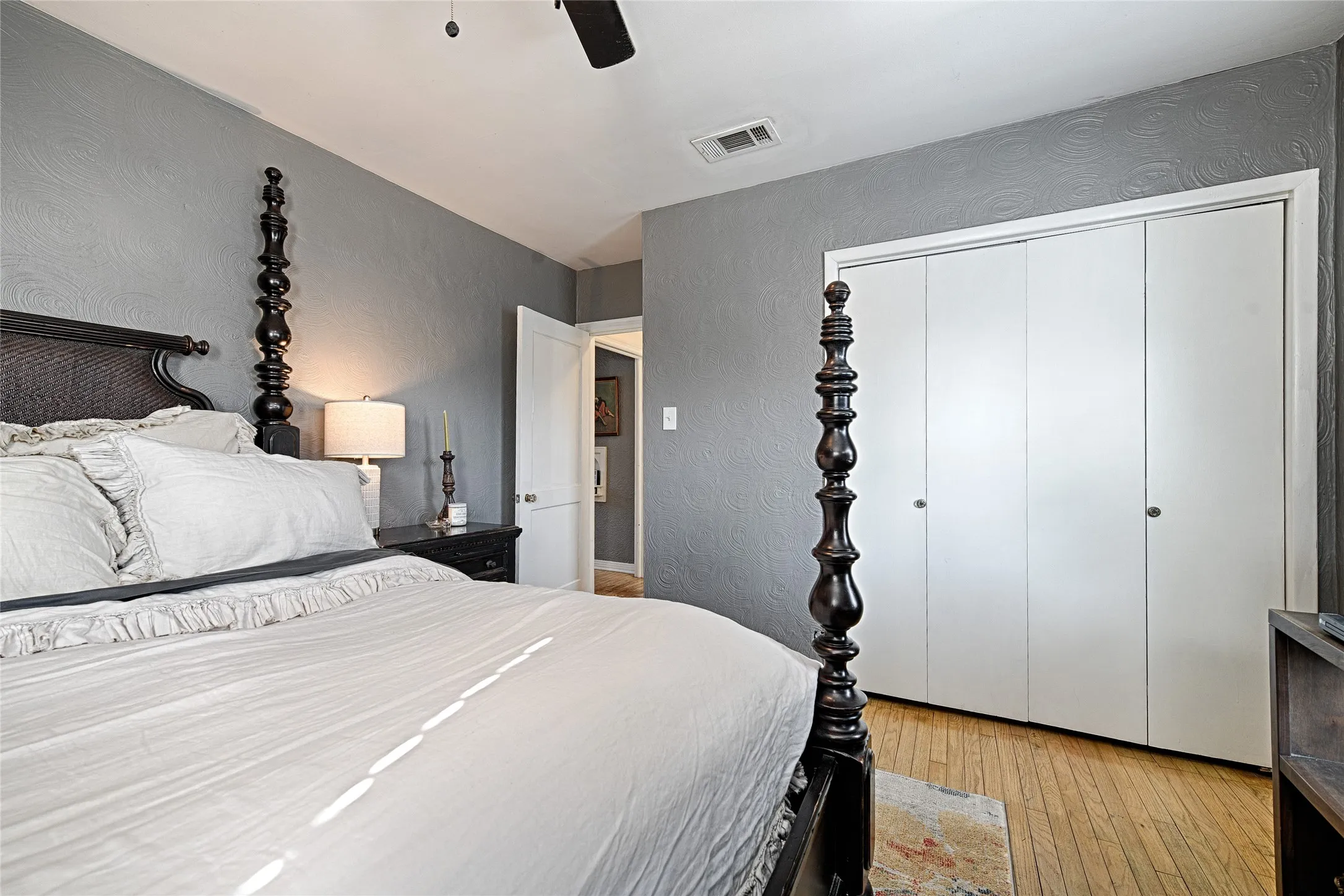Bedroom featuring a textured wall, light wood-style floors, a closet, ceiling fan and custom closet.