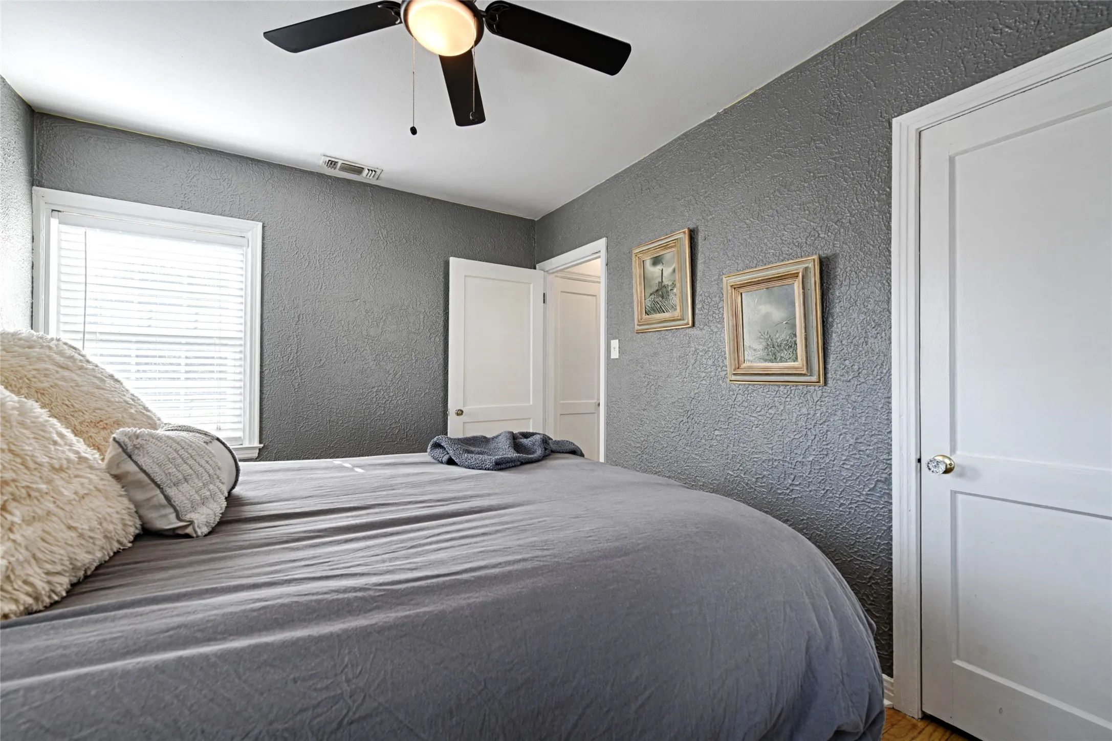Bedroom featuring a textured wall, a ceiling fan, and wood floors