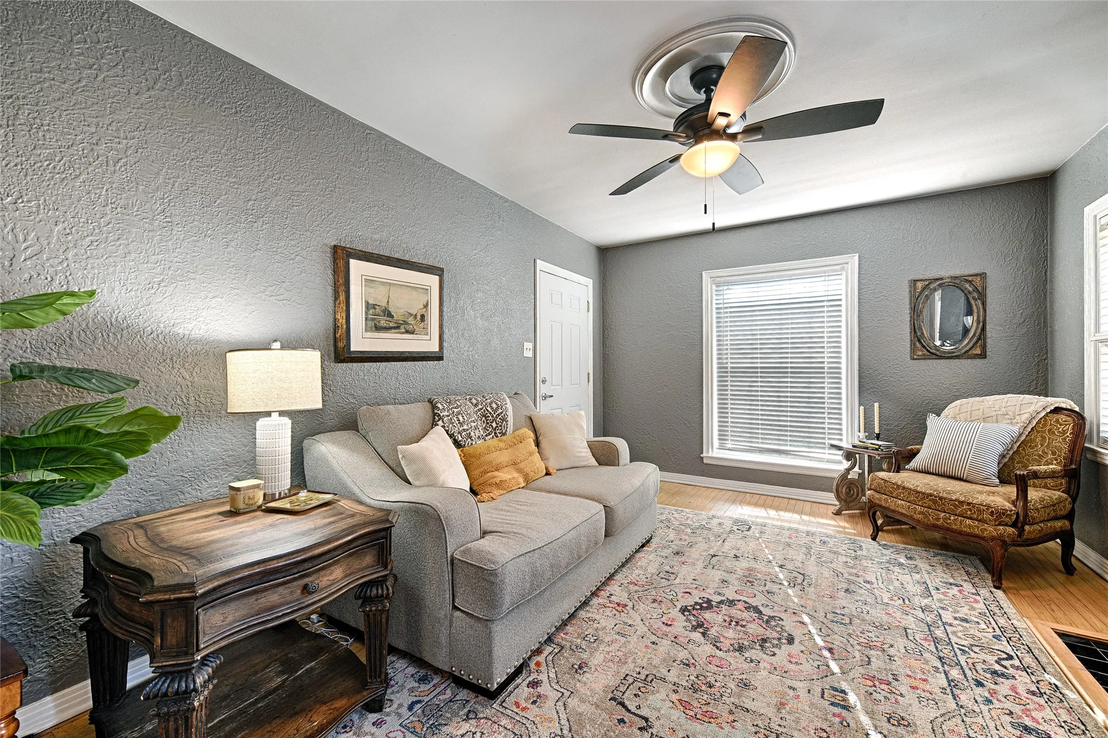 Living area featuring a textured wall, wood finished floors, and ceiling fan