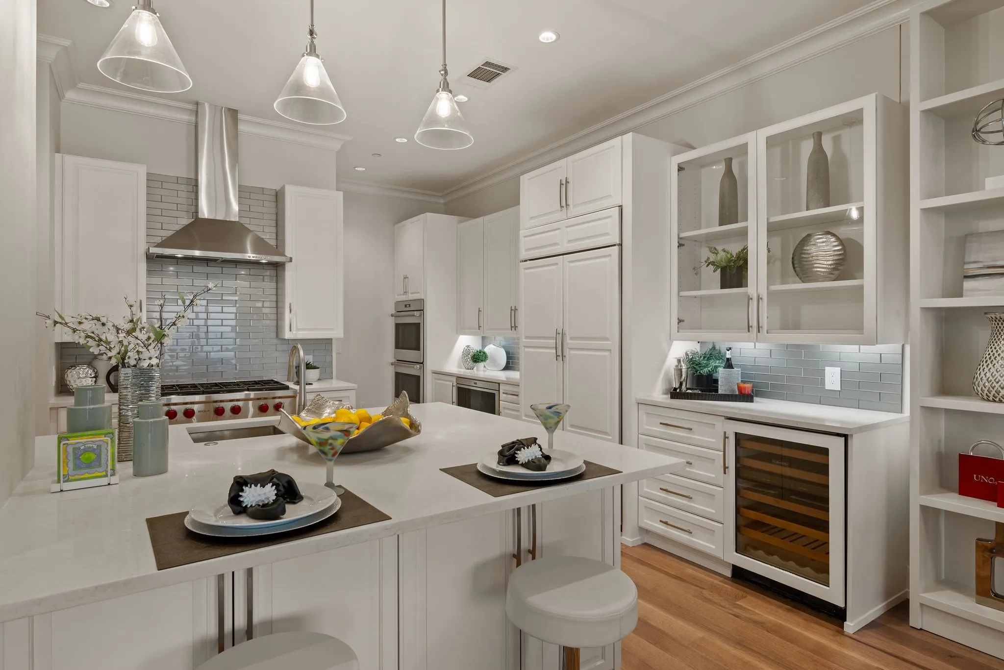 Kitchen with wall exhaust hood, stainless steel double oven, backsplash, and wine refrigerator