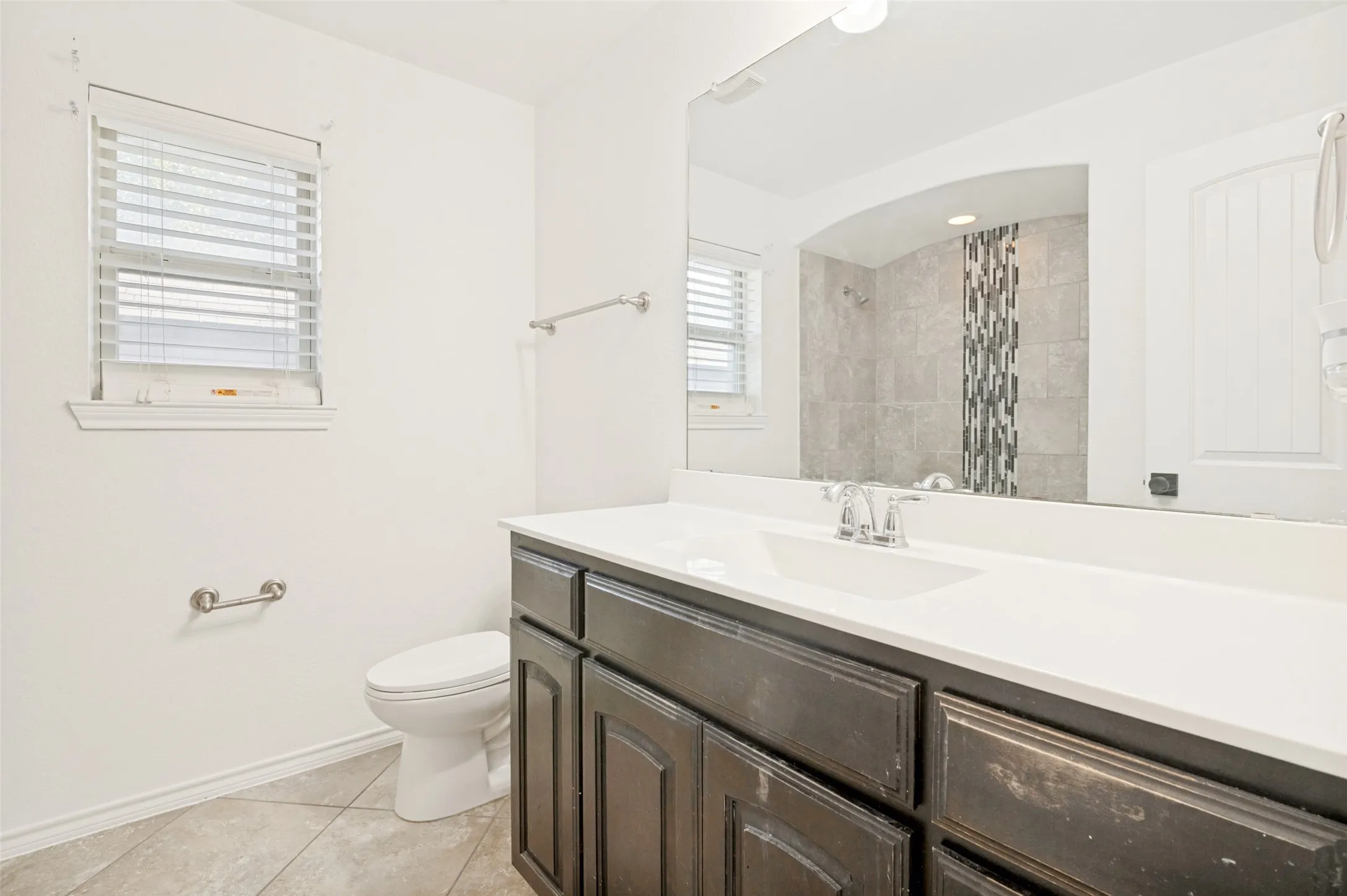 Bathroom featuring a dark wood-finish vanity with a white countertop and integrated sink