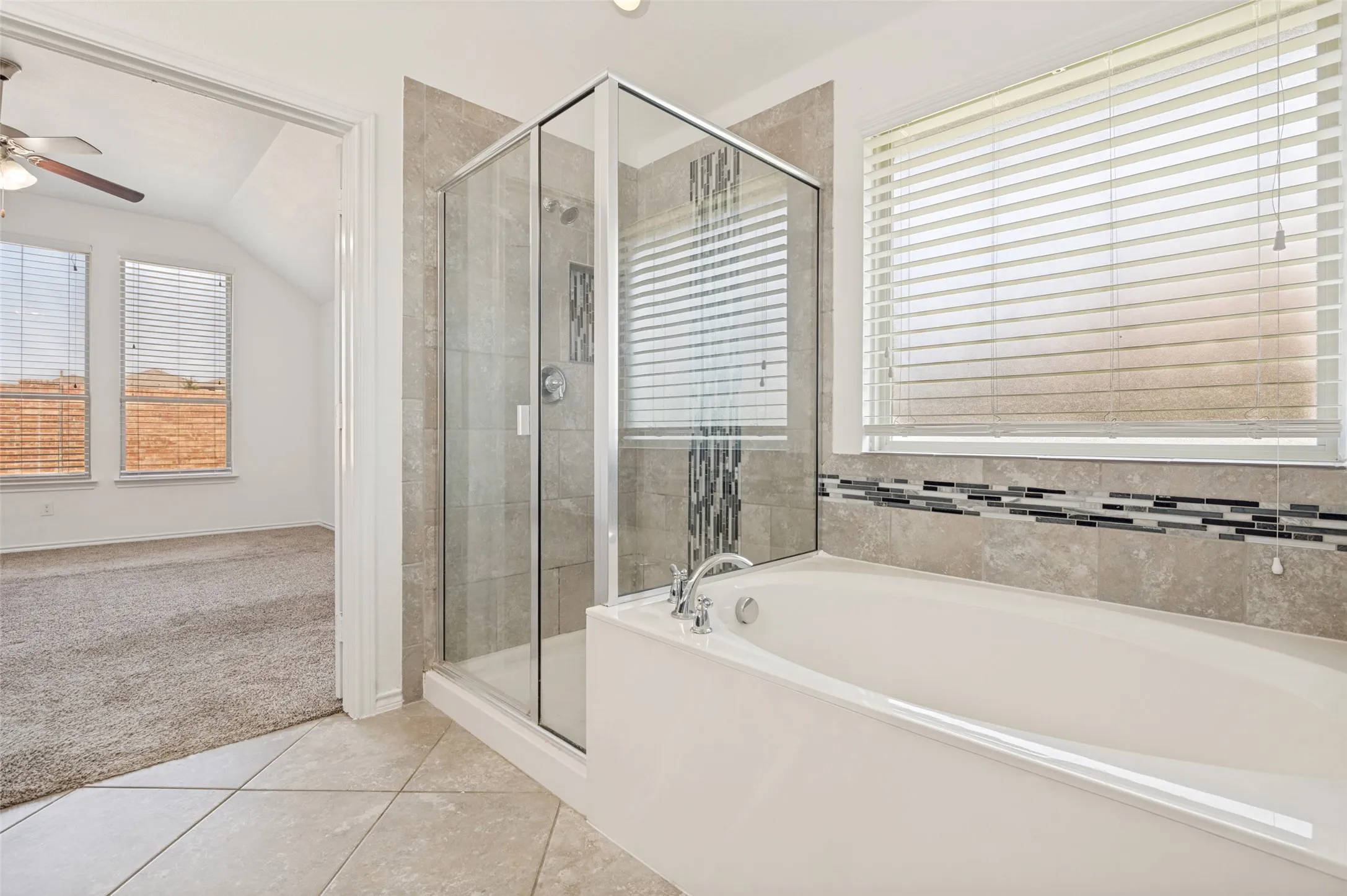 Bathroom featuring a walk-in glass shower, a built-in soaking tub, and tile flooring