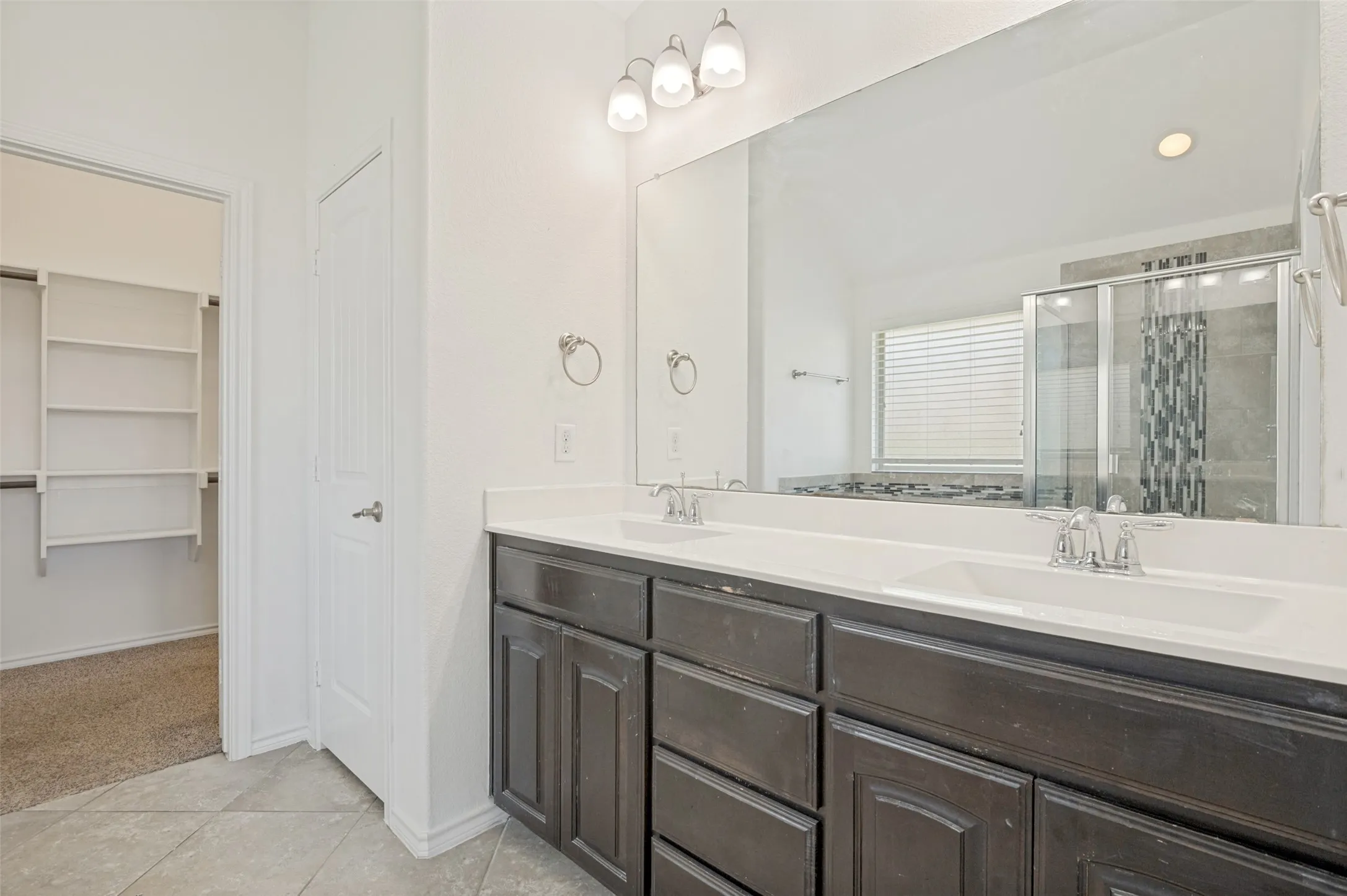 Double vanity with white countertops and dark cabinetry