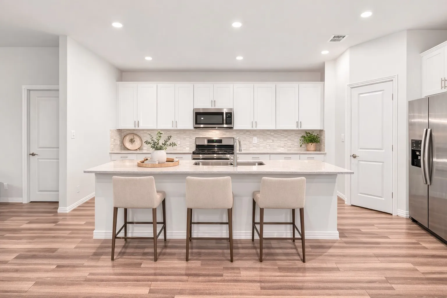Kitchen featuring white cabinetry, a breakfast bar area, a center island with sink, stainless steel appliances, and light wood finished floors