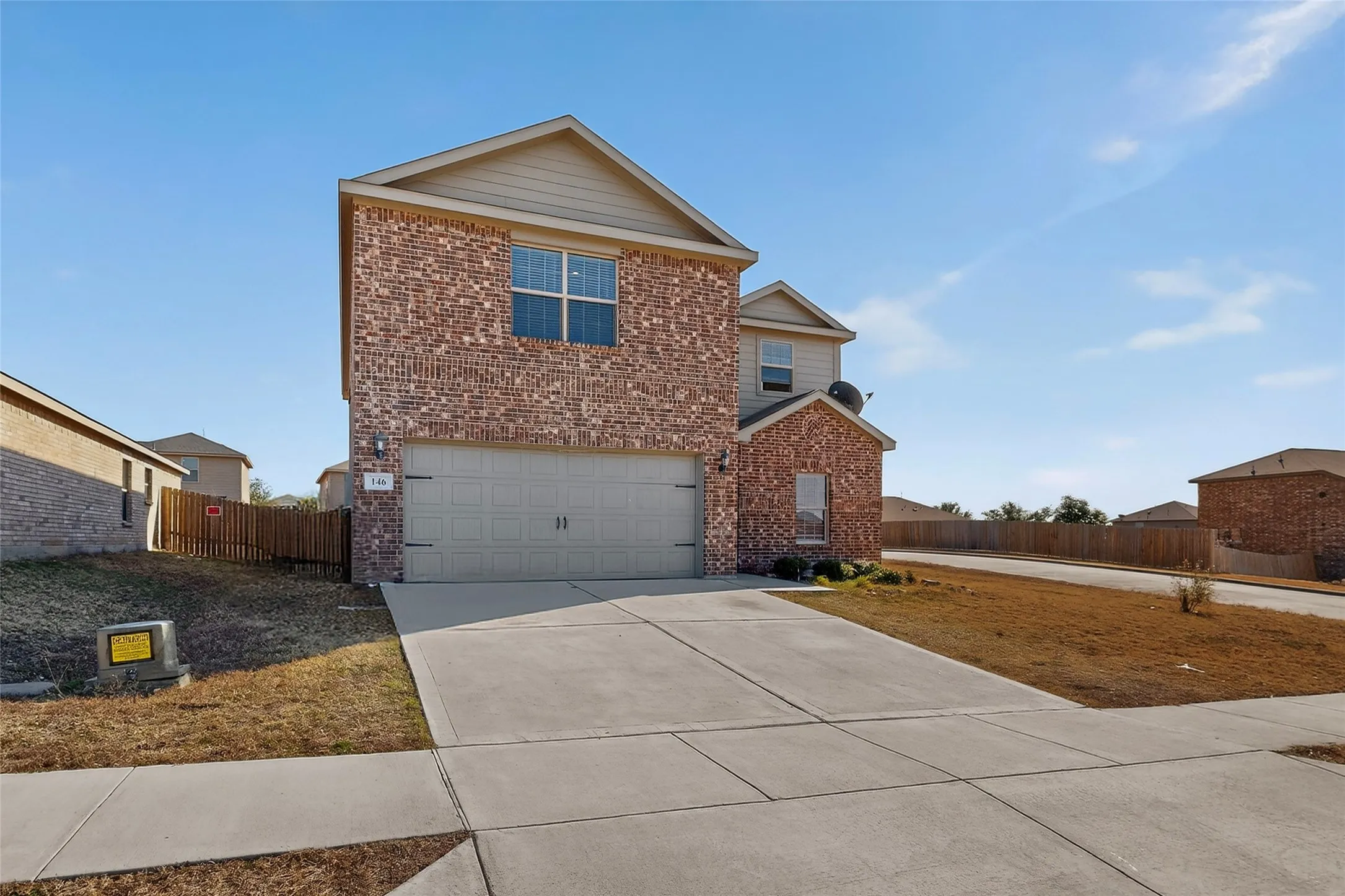 Traditional home featuring brick siding, driveway, and an attached garage