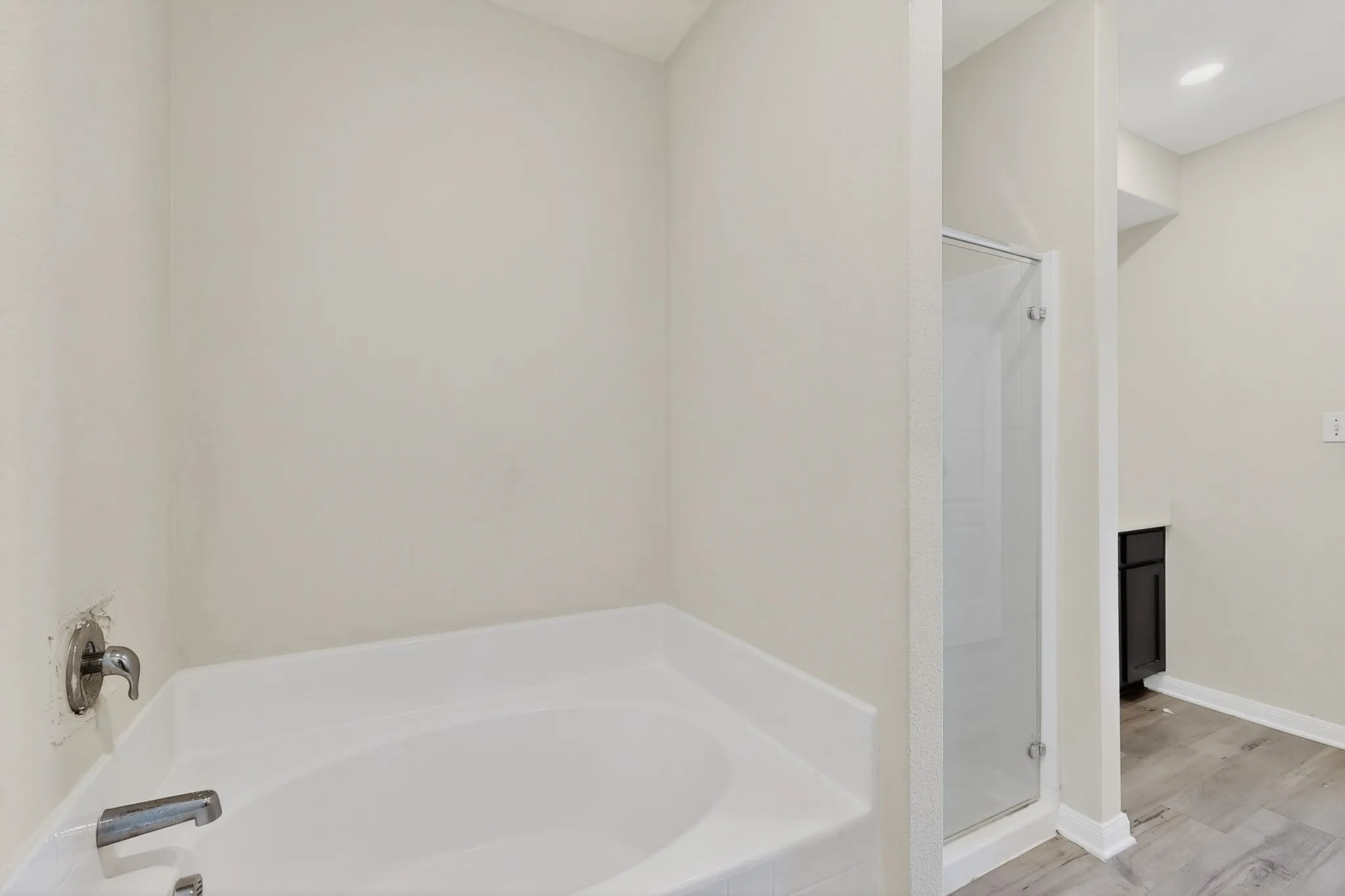 Full bath featuring a garden tub, a shower stall, vanity, wood finished floors, and recessed lighting