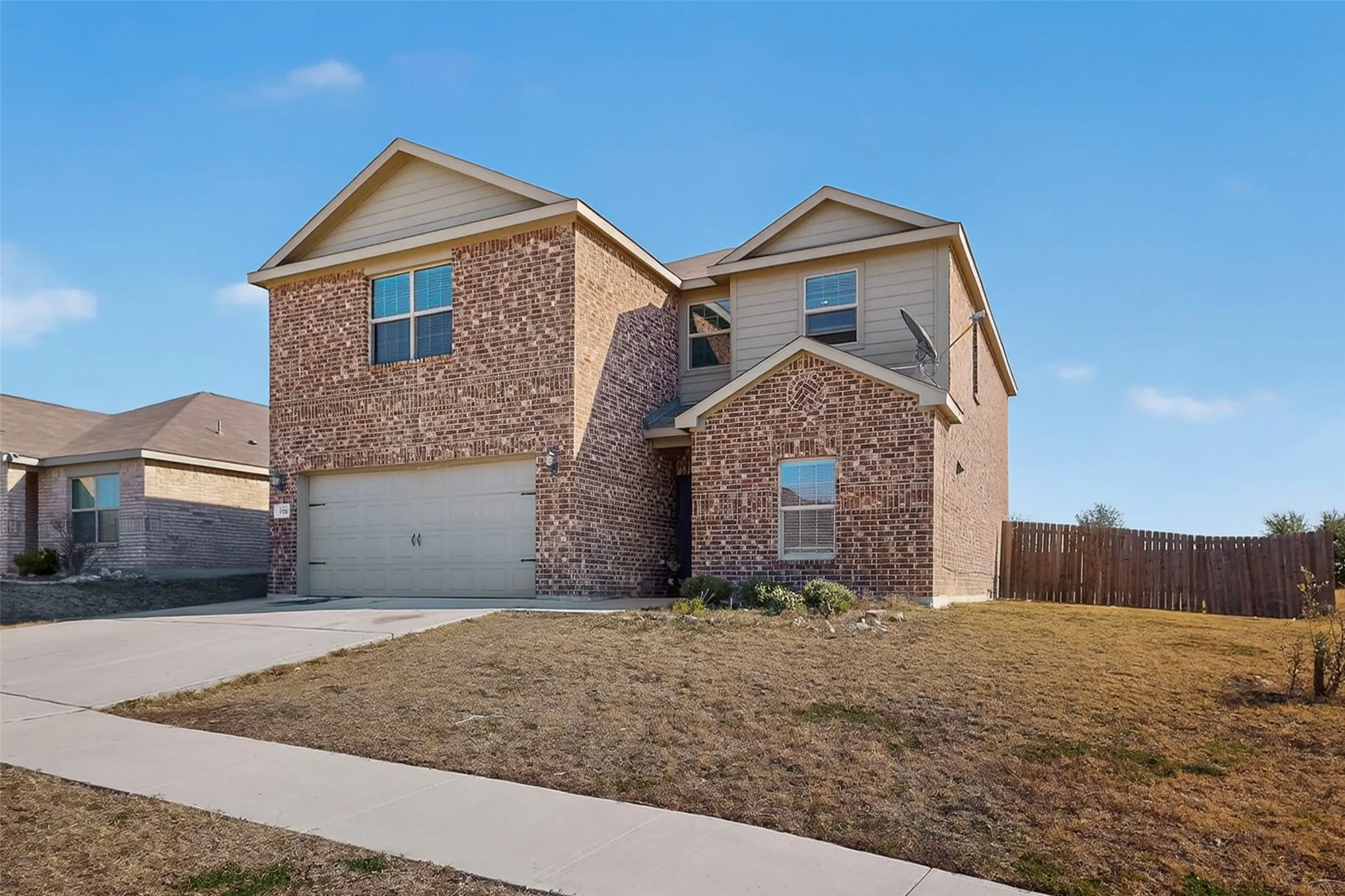 Traditional home featuring driveway, brick siding, and an attached garage