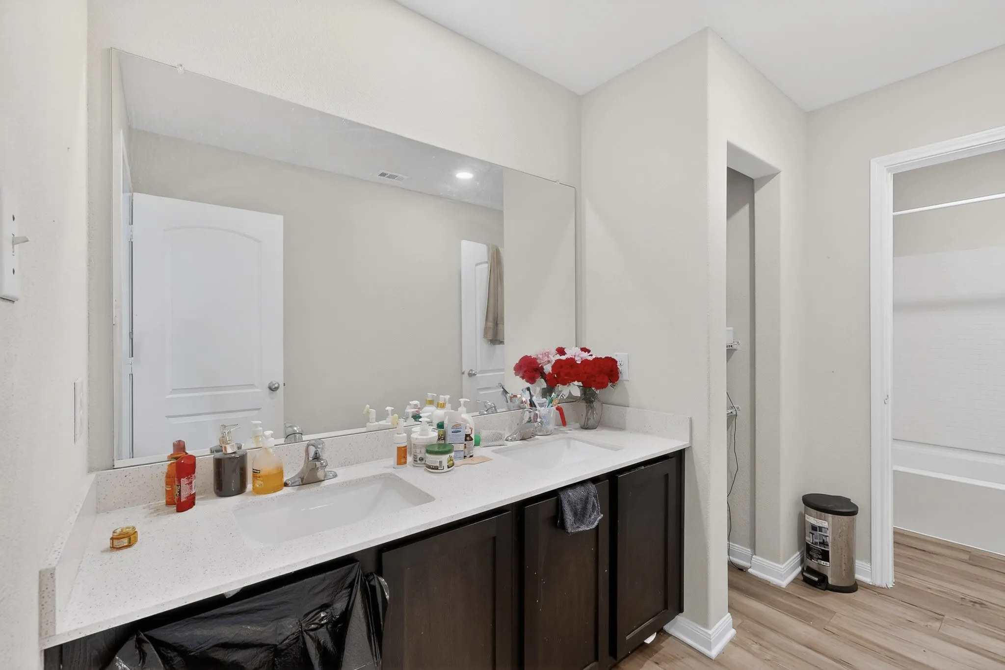 Bathroom with double vanity, light wood-type flooring, and bathing tub / shower combination