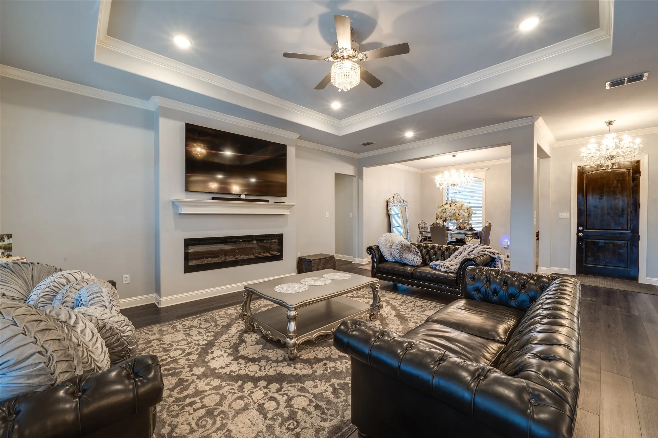 Elegant Living area with tray ceilings, a modern linear propane fireplace, and wood floors, creating a refined yet inviting space.