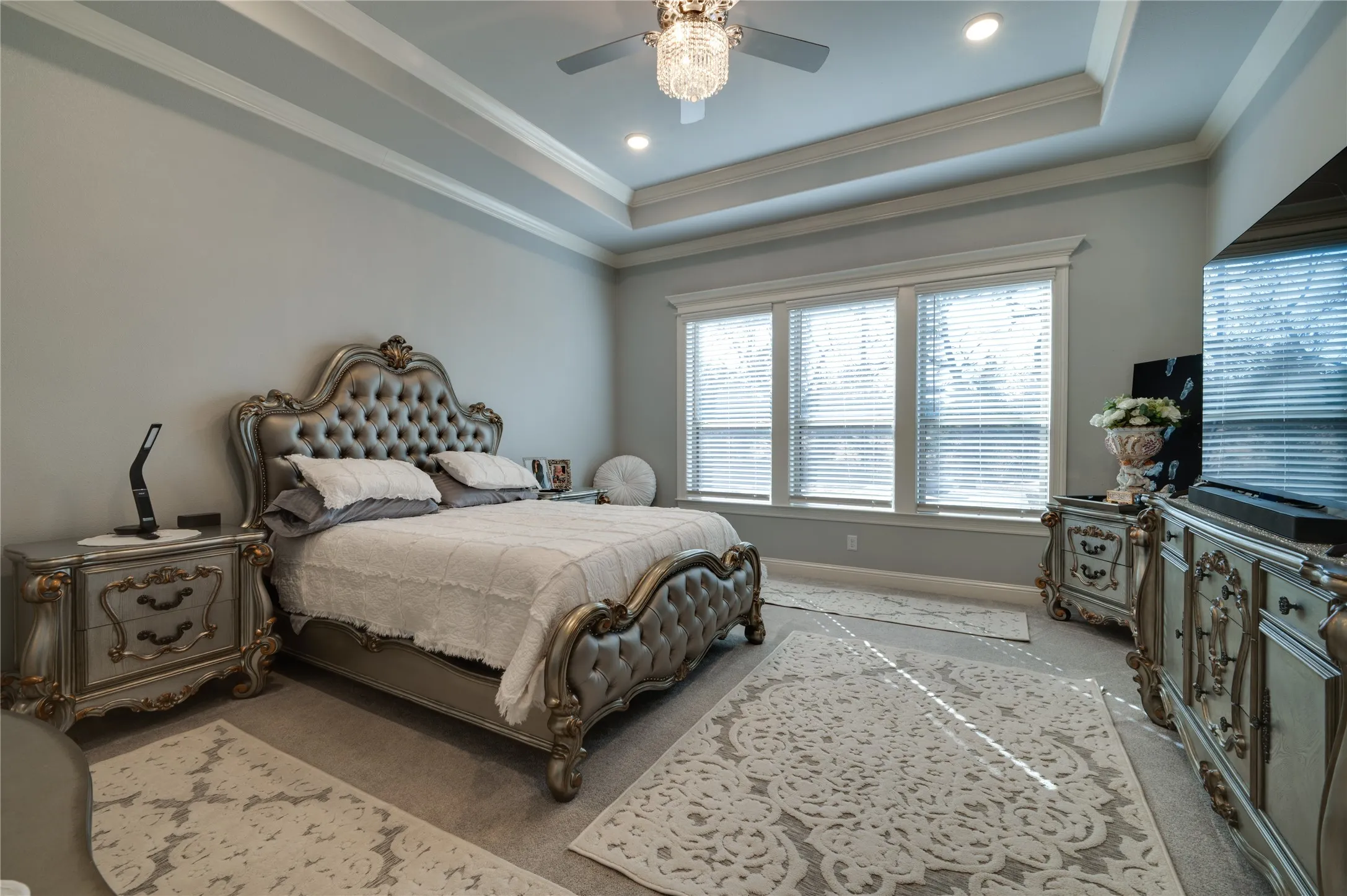 Spacious primary bedroom featuring tray ceilings and recessed can lighting for a clean, elegant look.