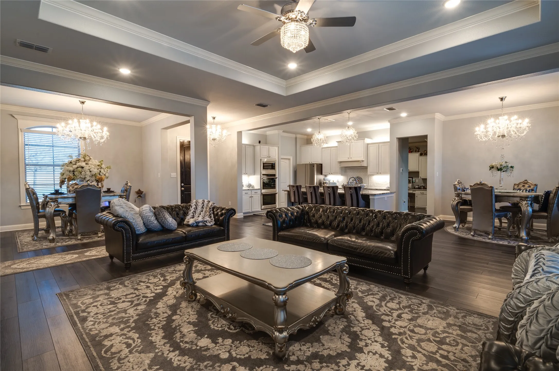 Formal dining, living area and chefs kitchen with wood flooring, tray ceilings and beautiful, modern light fixtures.