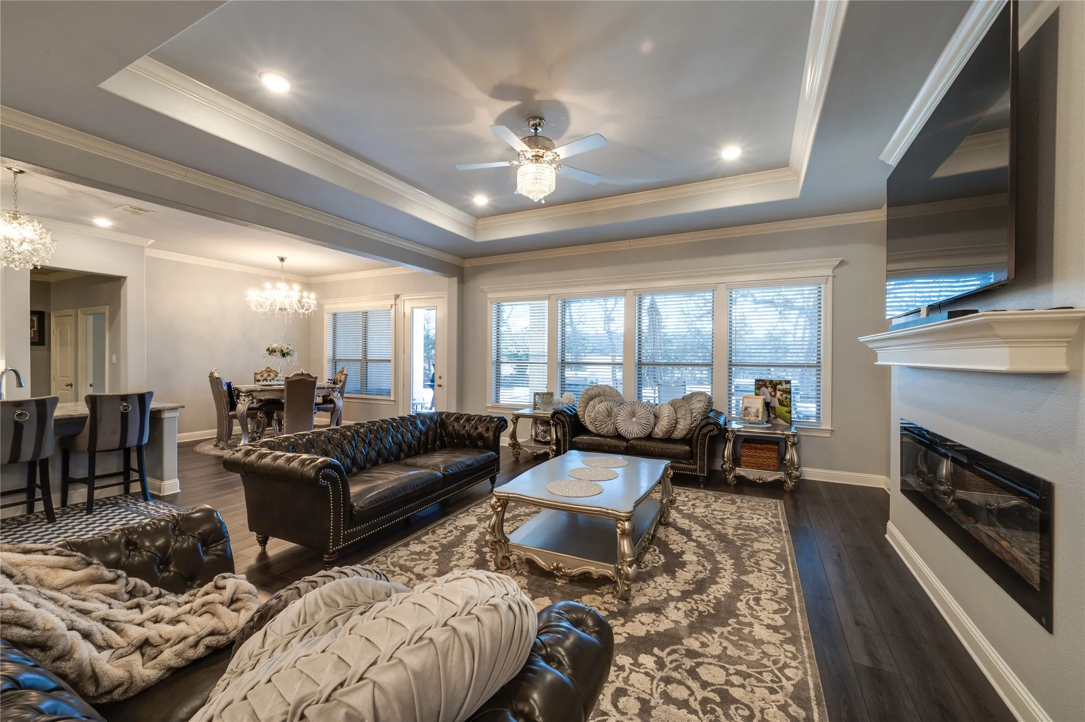 Elegant Living area with tray ceilings, a modern linear propane fireplace, and wood floors, creating a refined yet inviting space.
