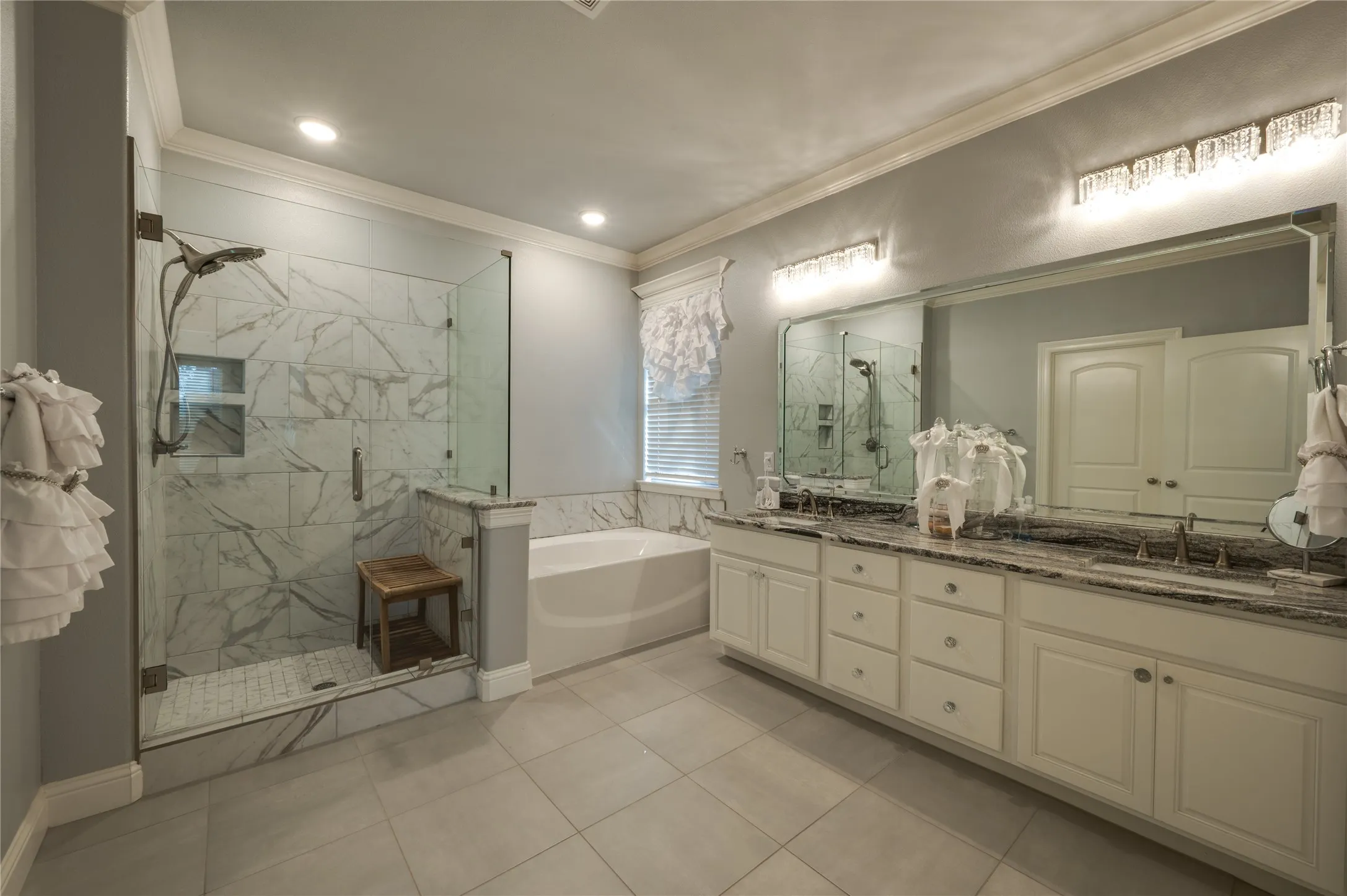 Spa-inspired primary bath with tile flooring, walk in shower, soaking garden tub and elegant granite countertops.