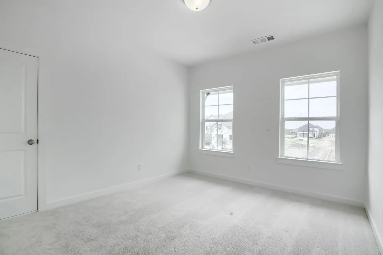 Bright interior room featuring light-colored carpeting, white painted walls, and two large windows with white trim