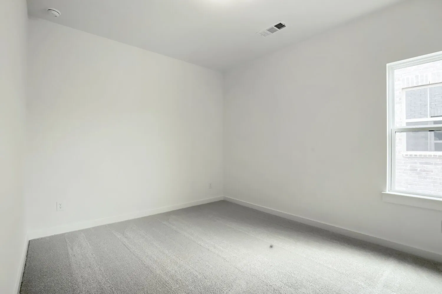 Bright interior room featuring a single window and light grey carpeting