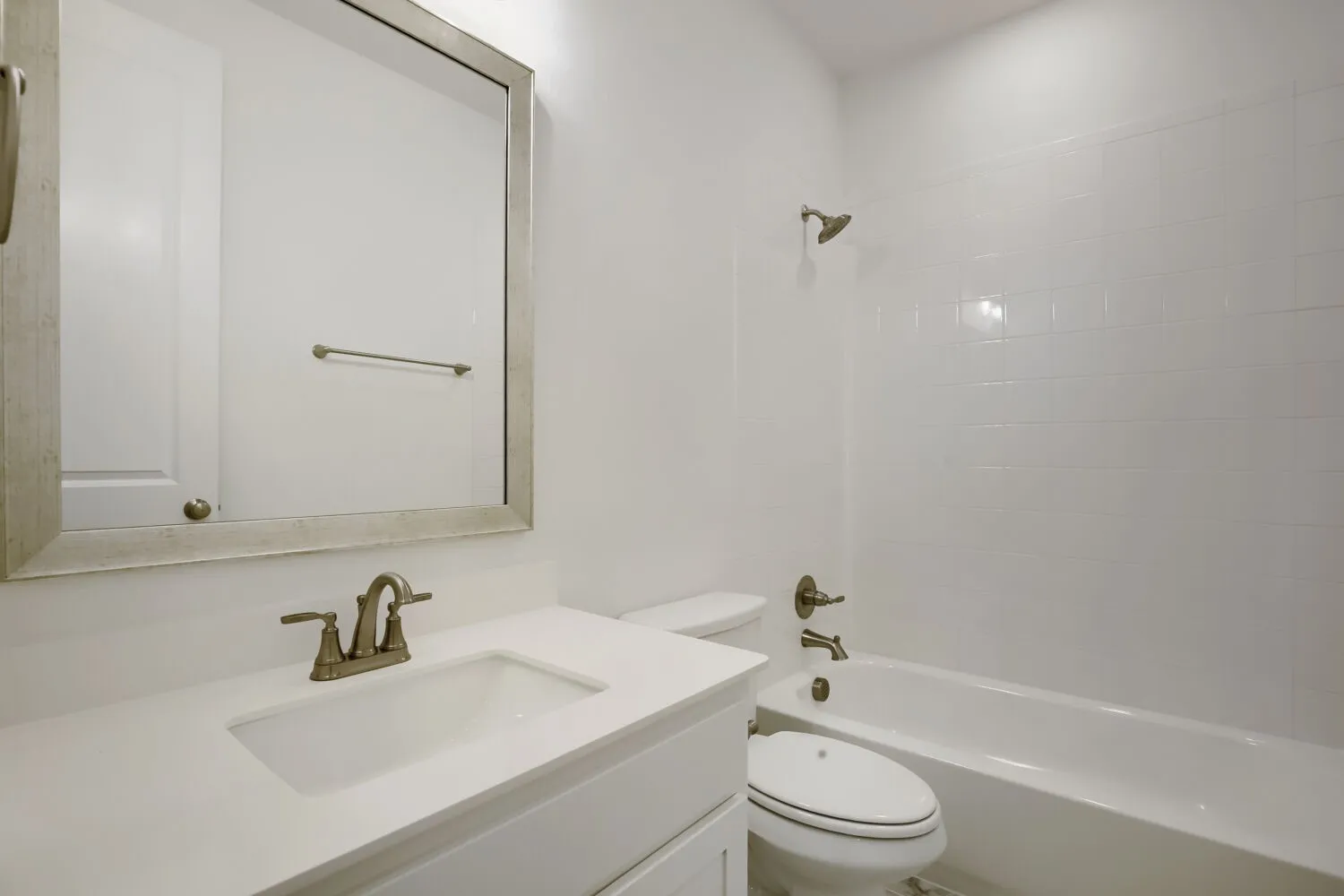 Bathroom featuring a white vanity with an integrated sink, a large framed mirror, and an antique brass-finish faucet