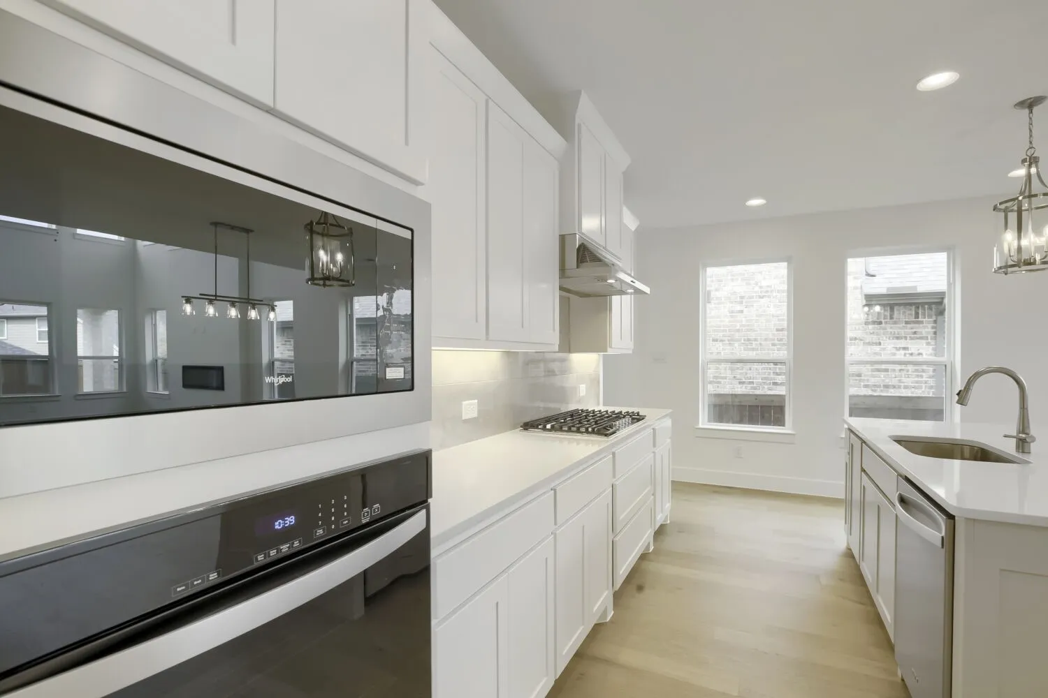 Modern kitchen featuring white cabinetry, light countertops, wood-finish flooring, a stainless steel gas range, and a built-in microwave and oven combination