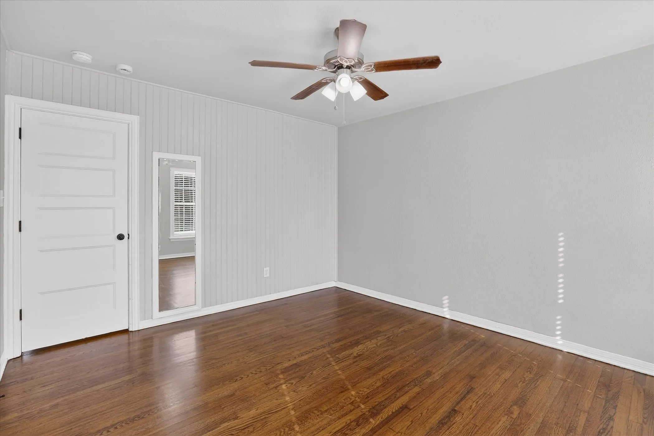 Third bedroom with ceiling fan and wood floors.