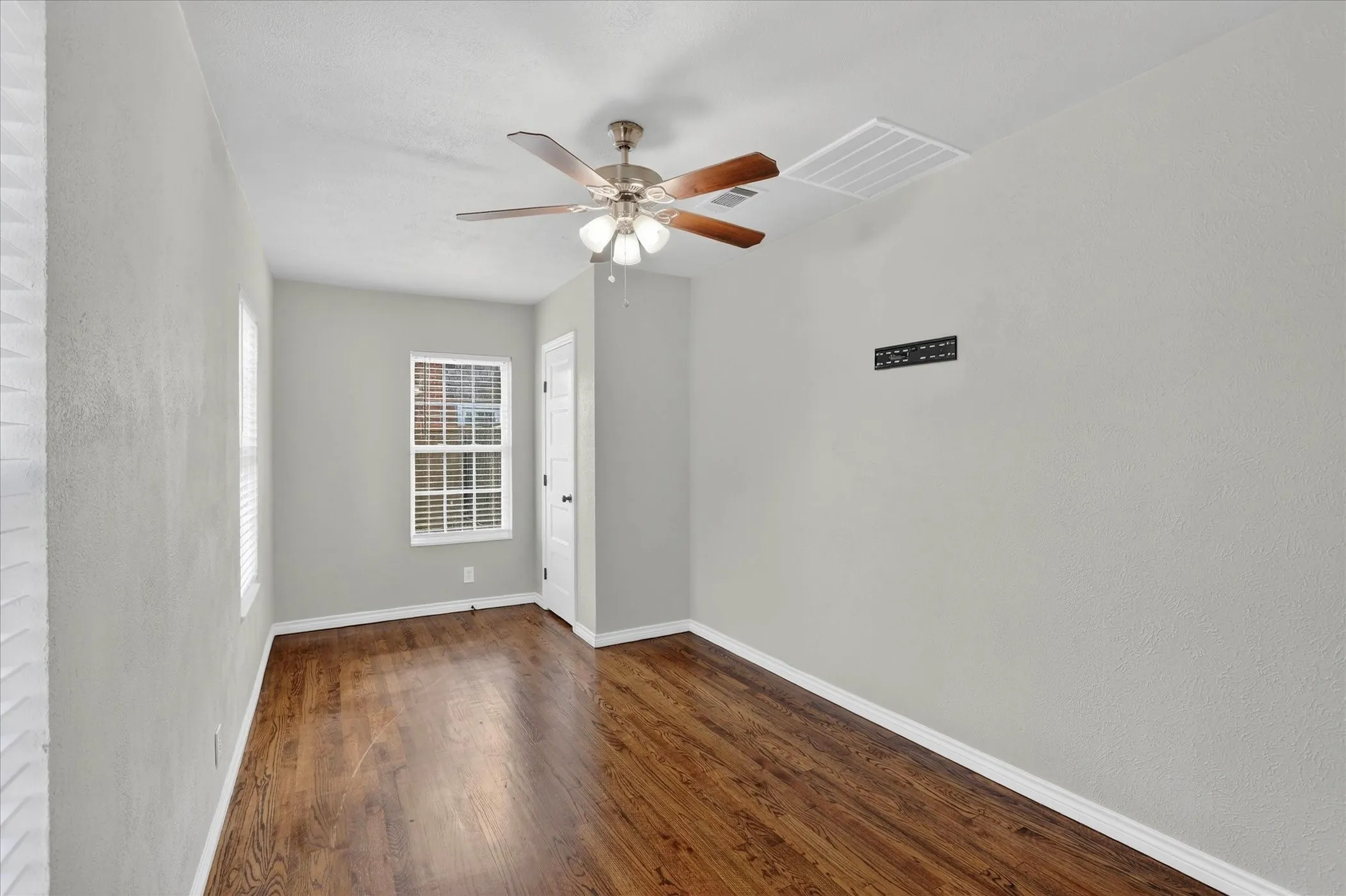 Front bedroom with on suite bathroom, ceiling fan and wood floors