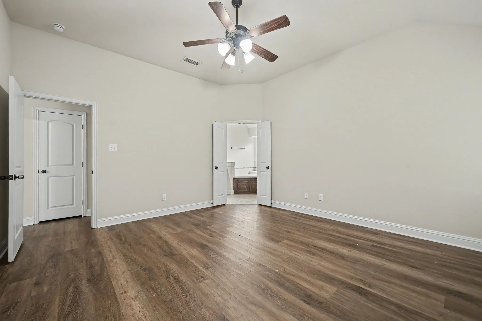Unfurnished bedroom featuring connected bathroom, ceiling fan, dark wood-style floors, and lofted ceiling