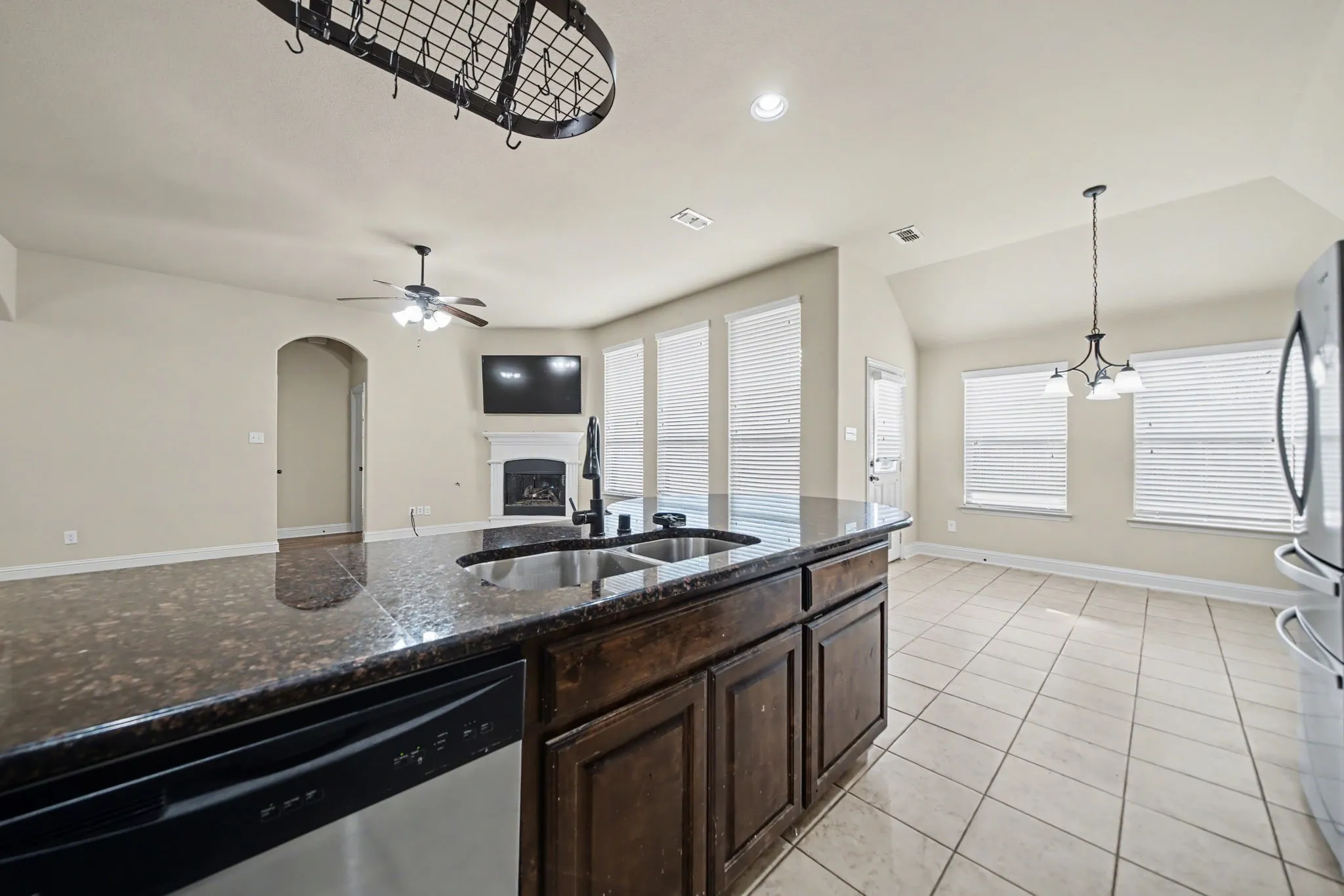 Kitchen featuring dark brown cabinets, a fireplace, stainless steel appliances, dark stone countertops, and vaulted ceiling