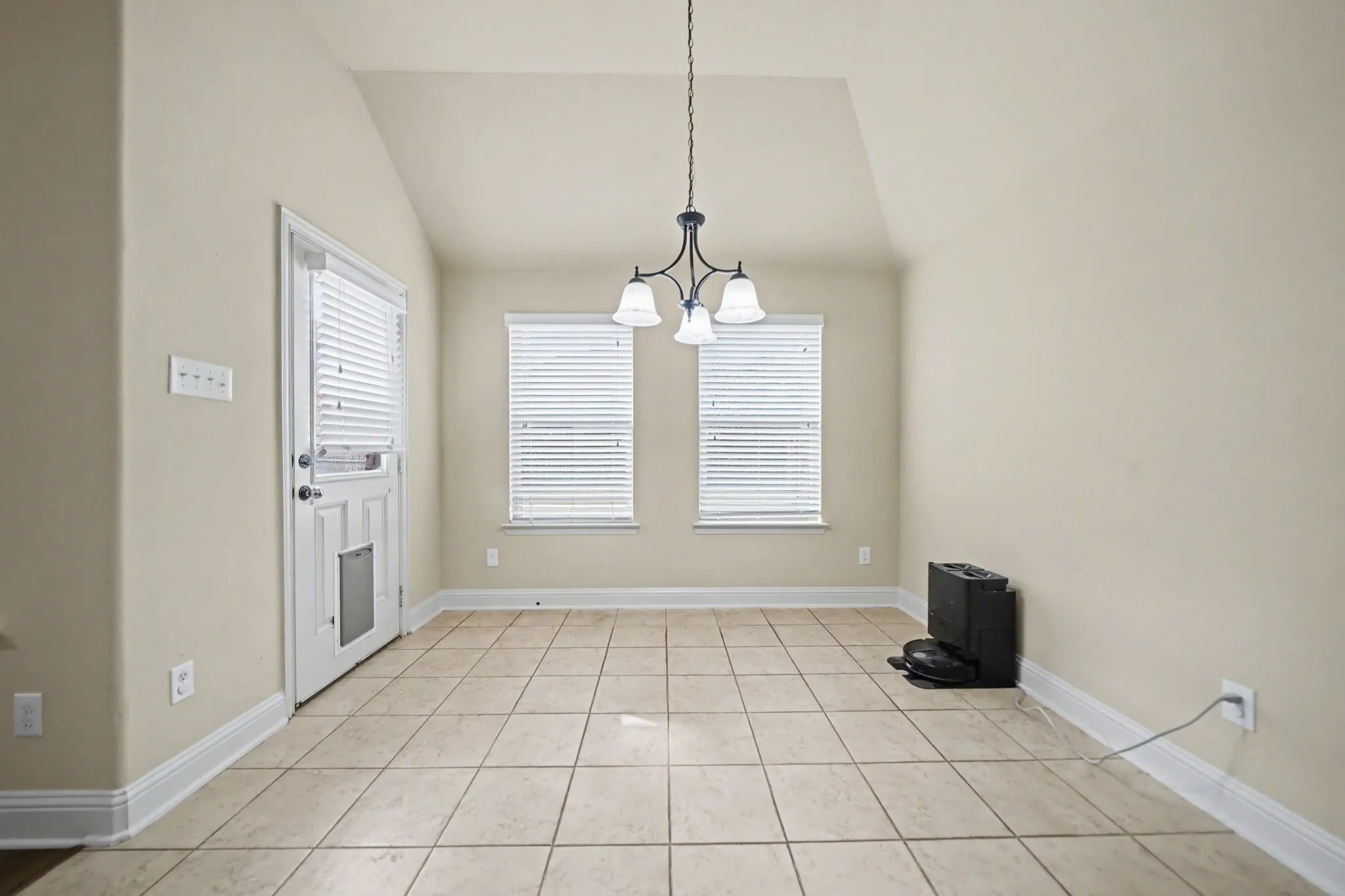 Unfurnished dining area featuring a chandelier, vaulted ceiling, and light tile patterned flooring