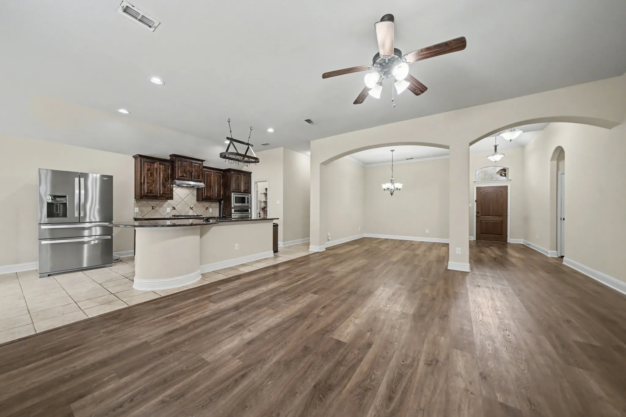 Unfurnished living room with a ceiling fan, recessed lighting, light wood-style floors, and a chandelier