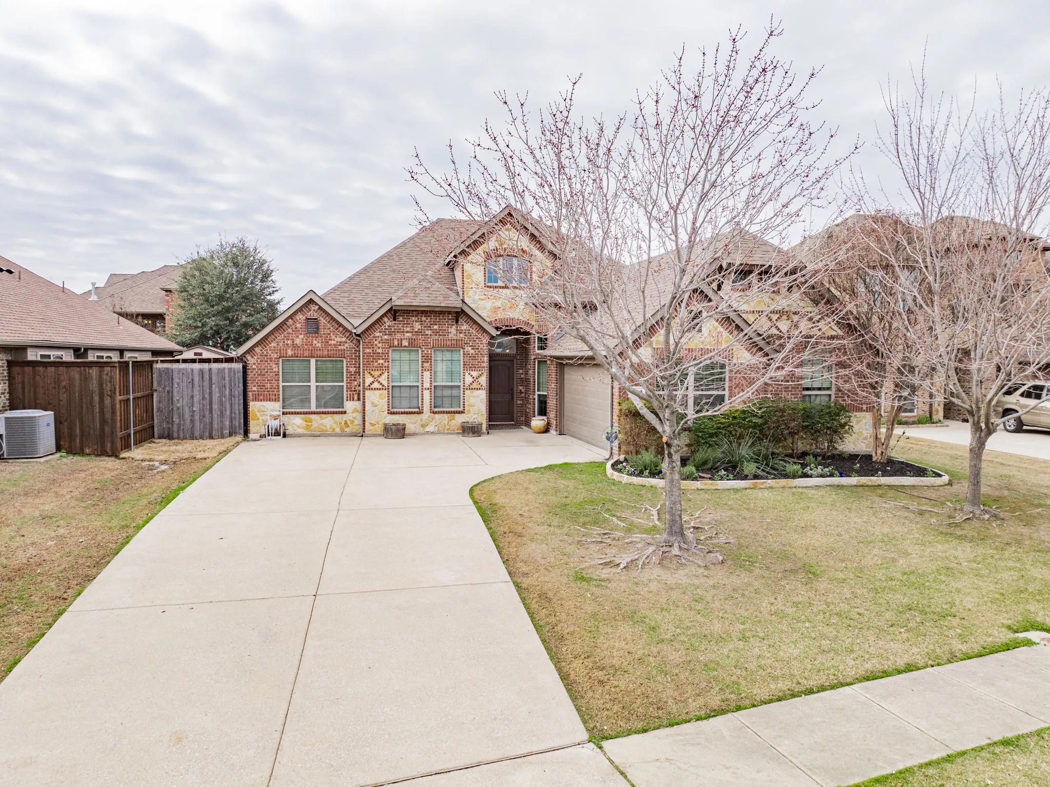 Craftsman-style house featuring stone siding, brick siding, and driveway