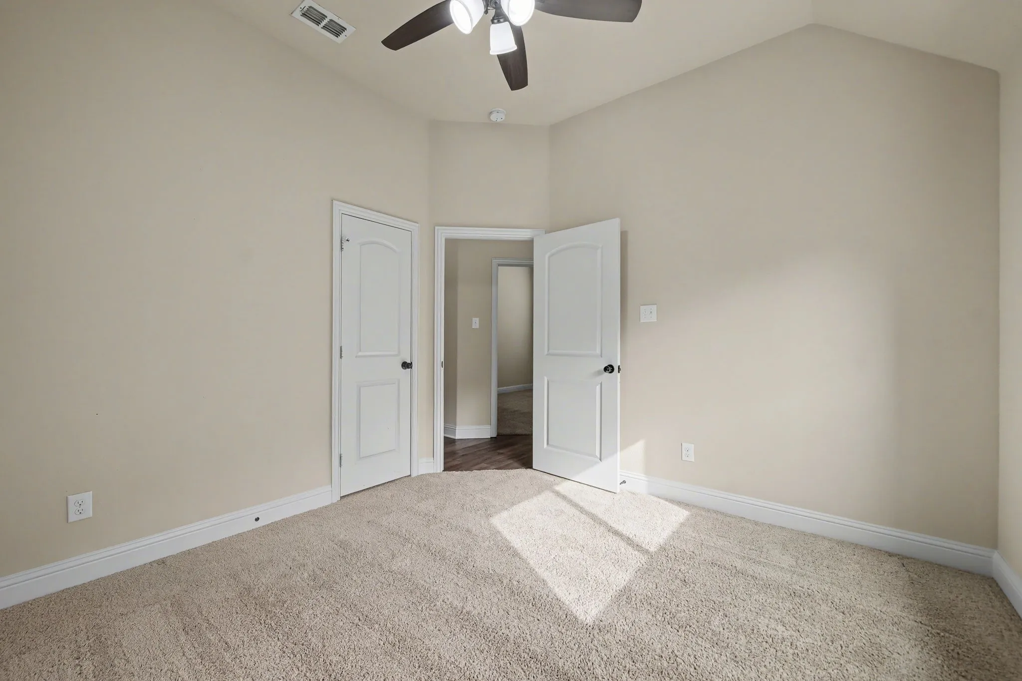 Unfurnished bedroom featuring light carpet, lofted ceiling, and a ceiling fan