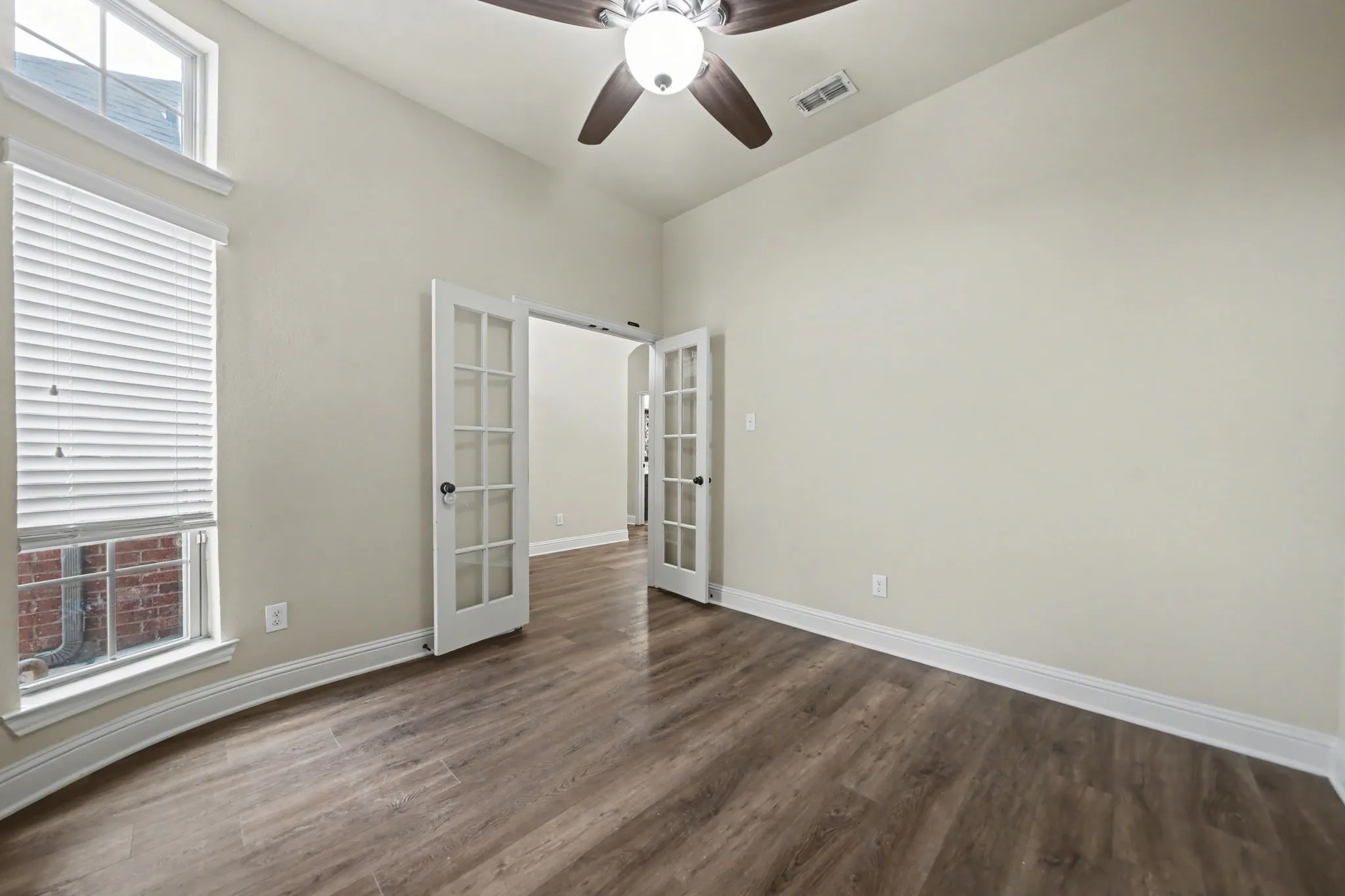 Unfurnished room featuring french doors, a ceiling fan, dark wood-style flooring, and a towering ceiling