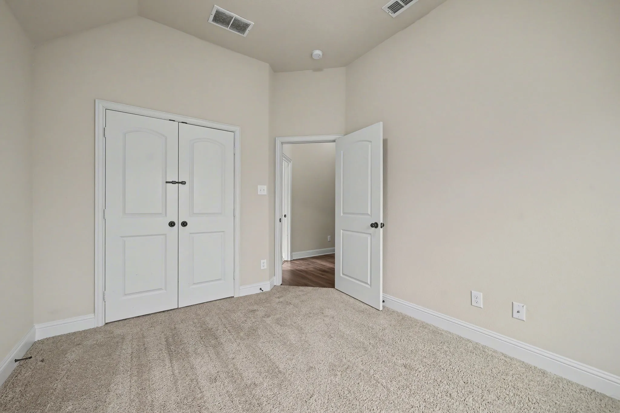 Unfurnished bedroom with light carpet, a closet, and lofted ceiling
