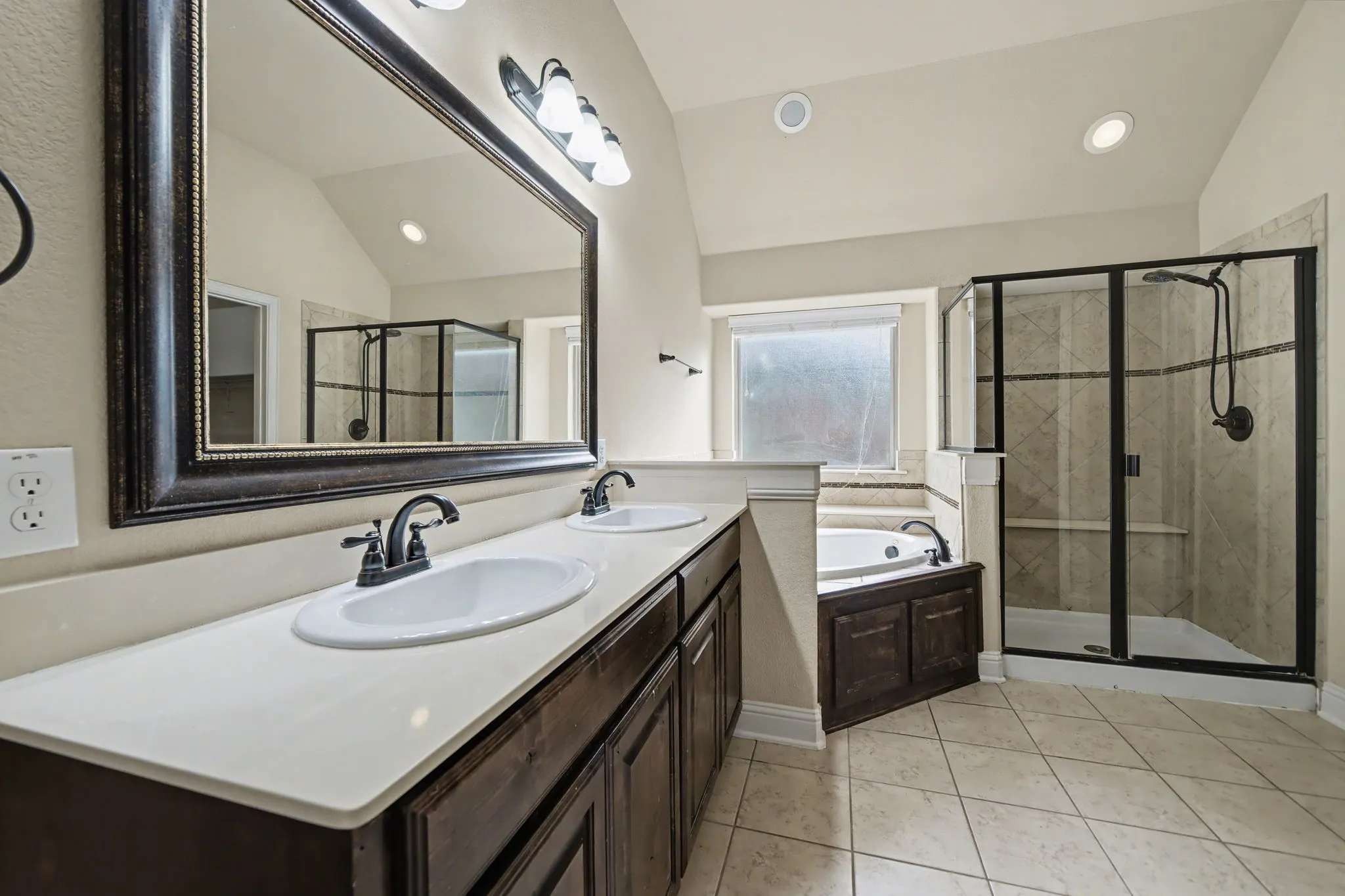 Full bath with vaulted ceiling, a bath, double vanity, a shower stall, and light tile patterned floors