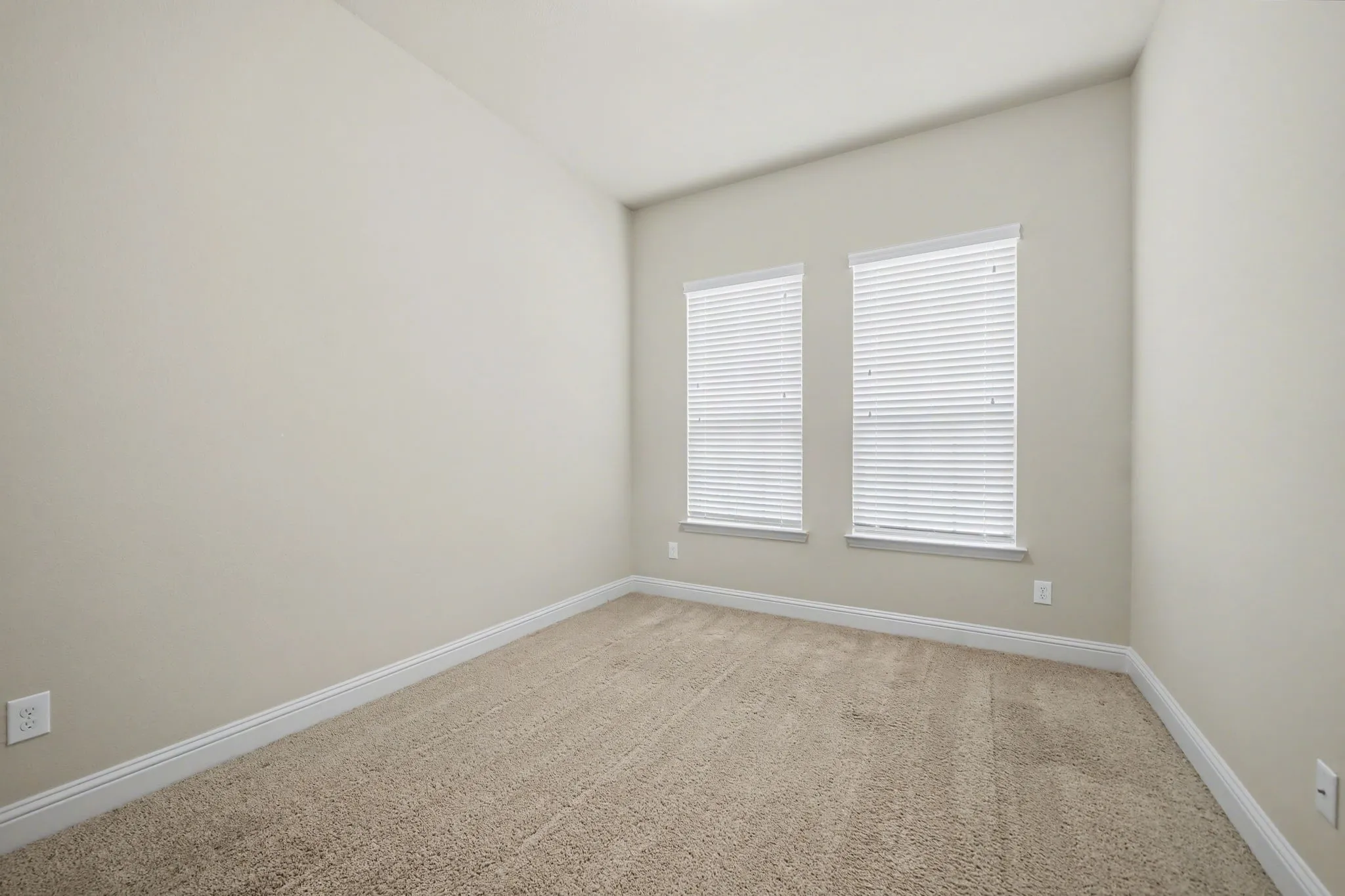 Unfurnished room featuring baseboards and light carpet