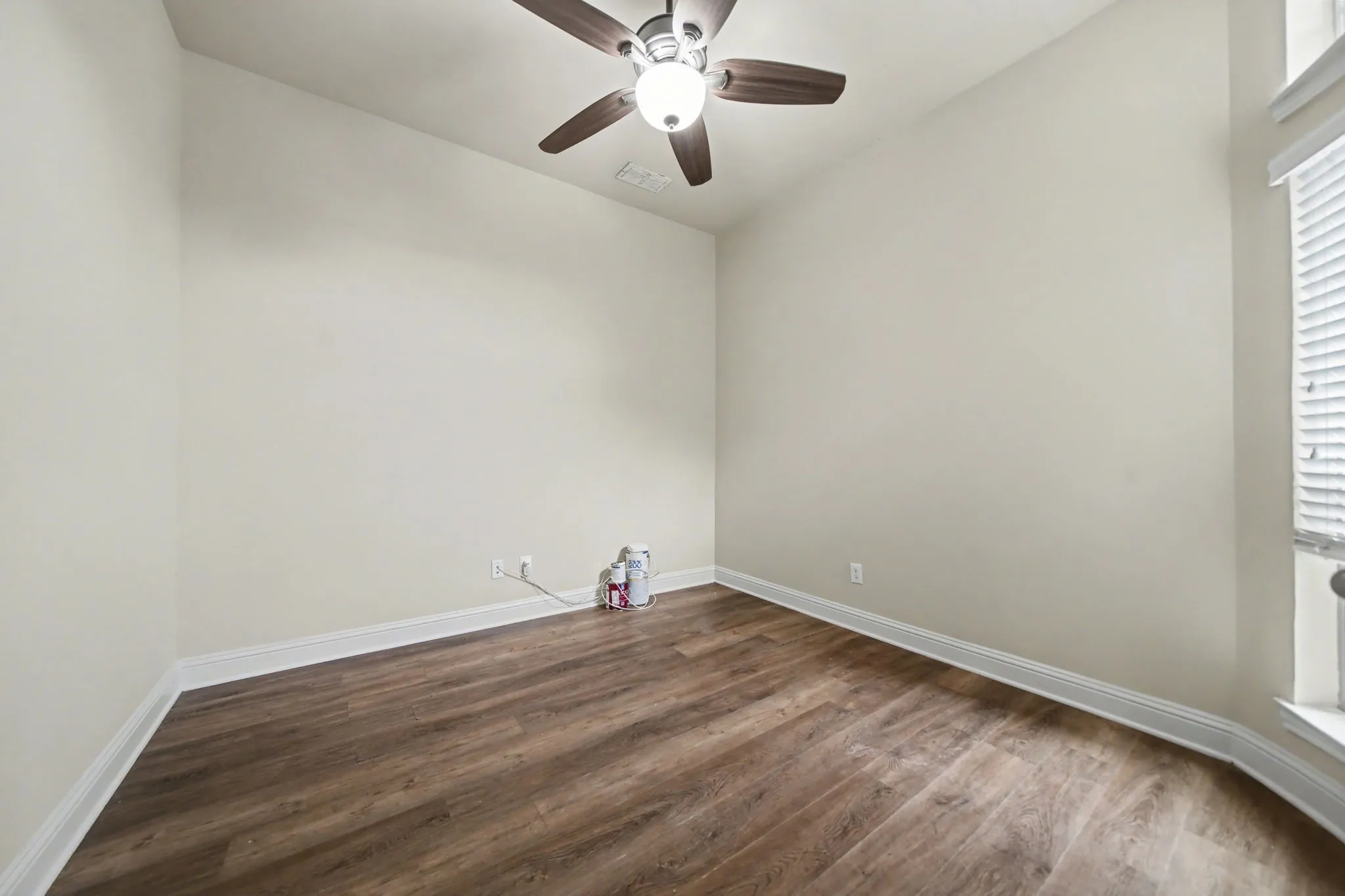 Spare room featuring dark wood-style floors, ceiling fan, and healthy amount of natural light