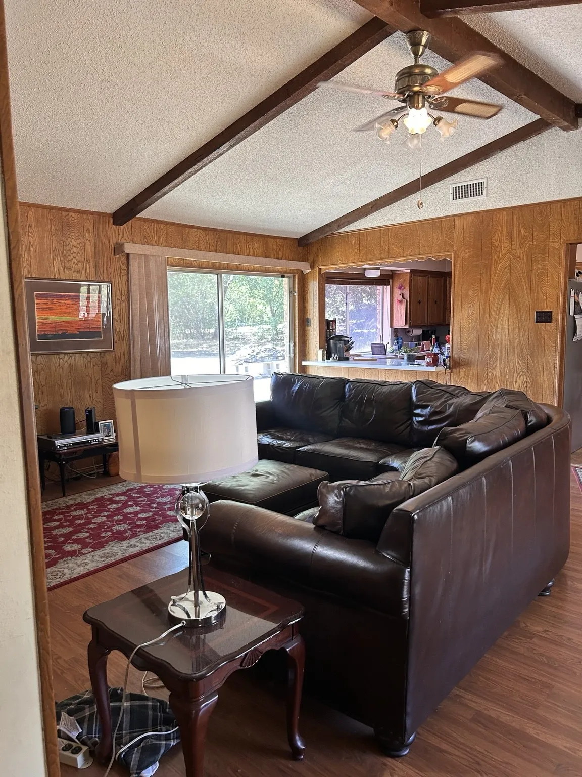 Vaulted ceiling with exposed wood beams, wood-finish flooring, and wood-paneled walls