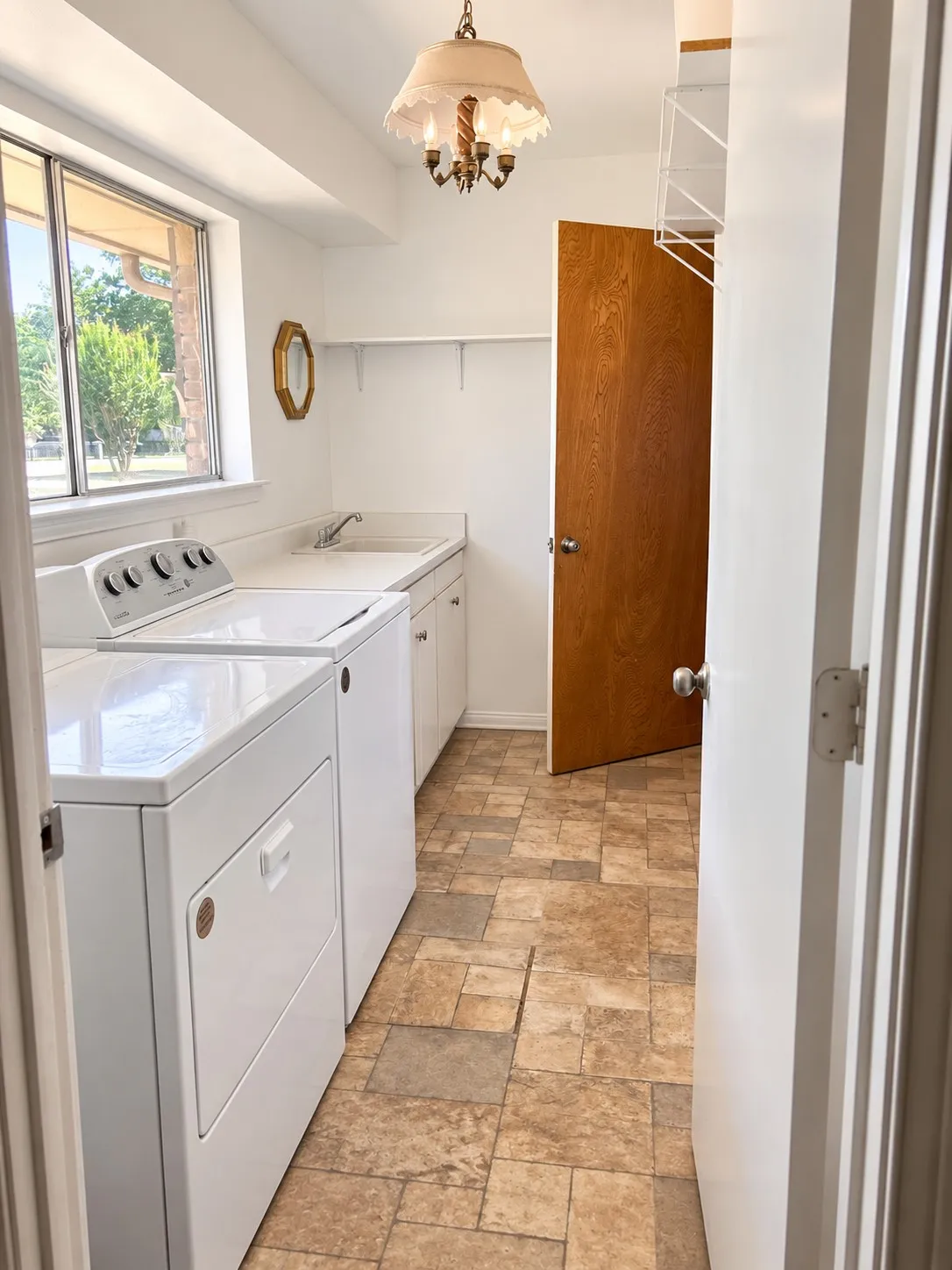 Utility room with wood-finish flooring, built-in cabinetry, an integrated sink, and a window for natural light