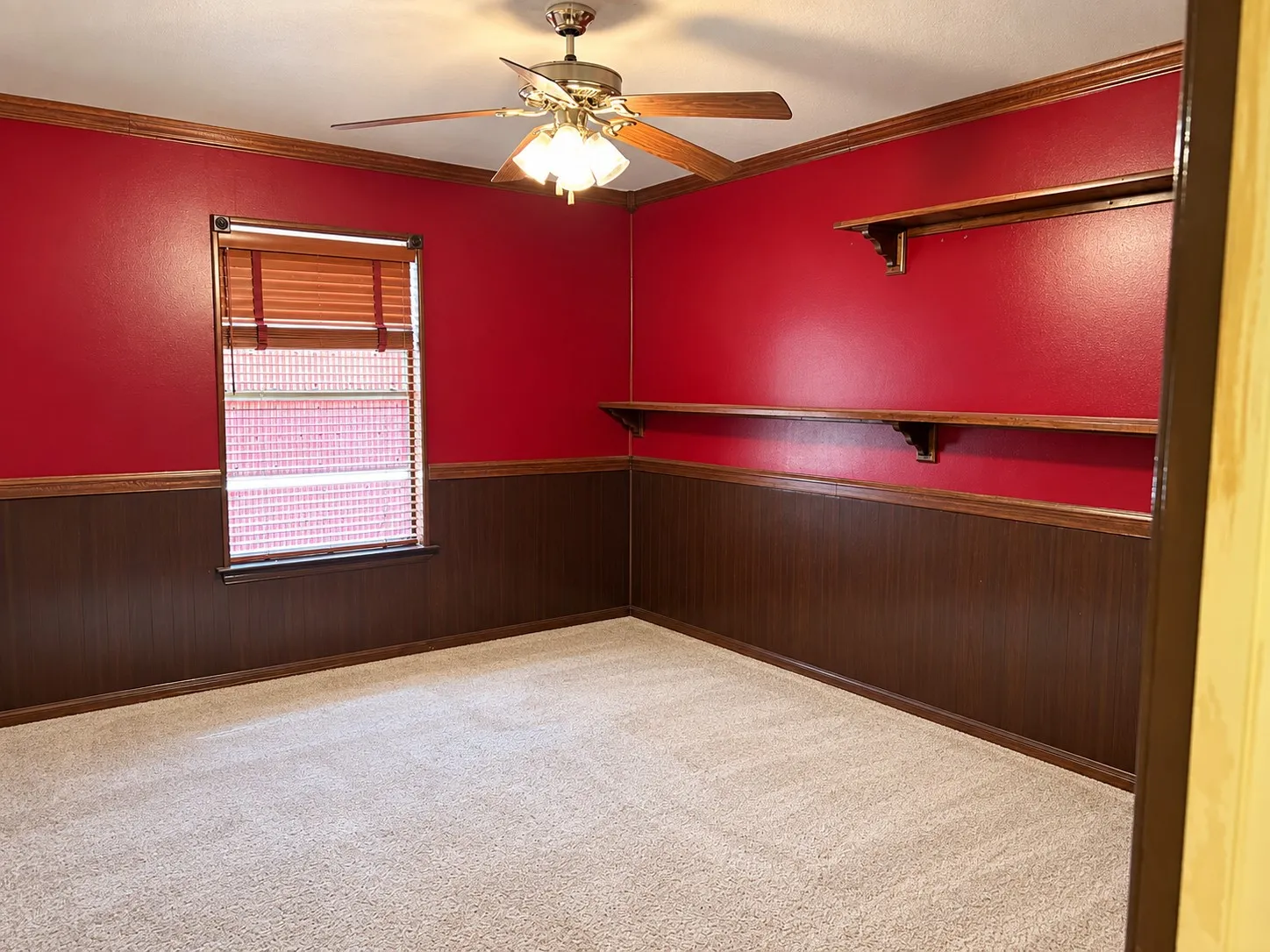 Wall-to-wall carpeting, wood-finish wainscoting, and a ceiling fan with integrated lighting
