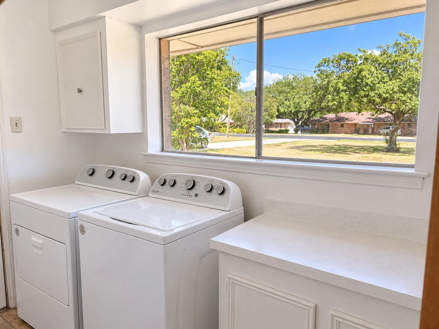 White cabinetry with built-in storage, white countertop, and large window