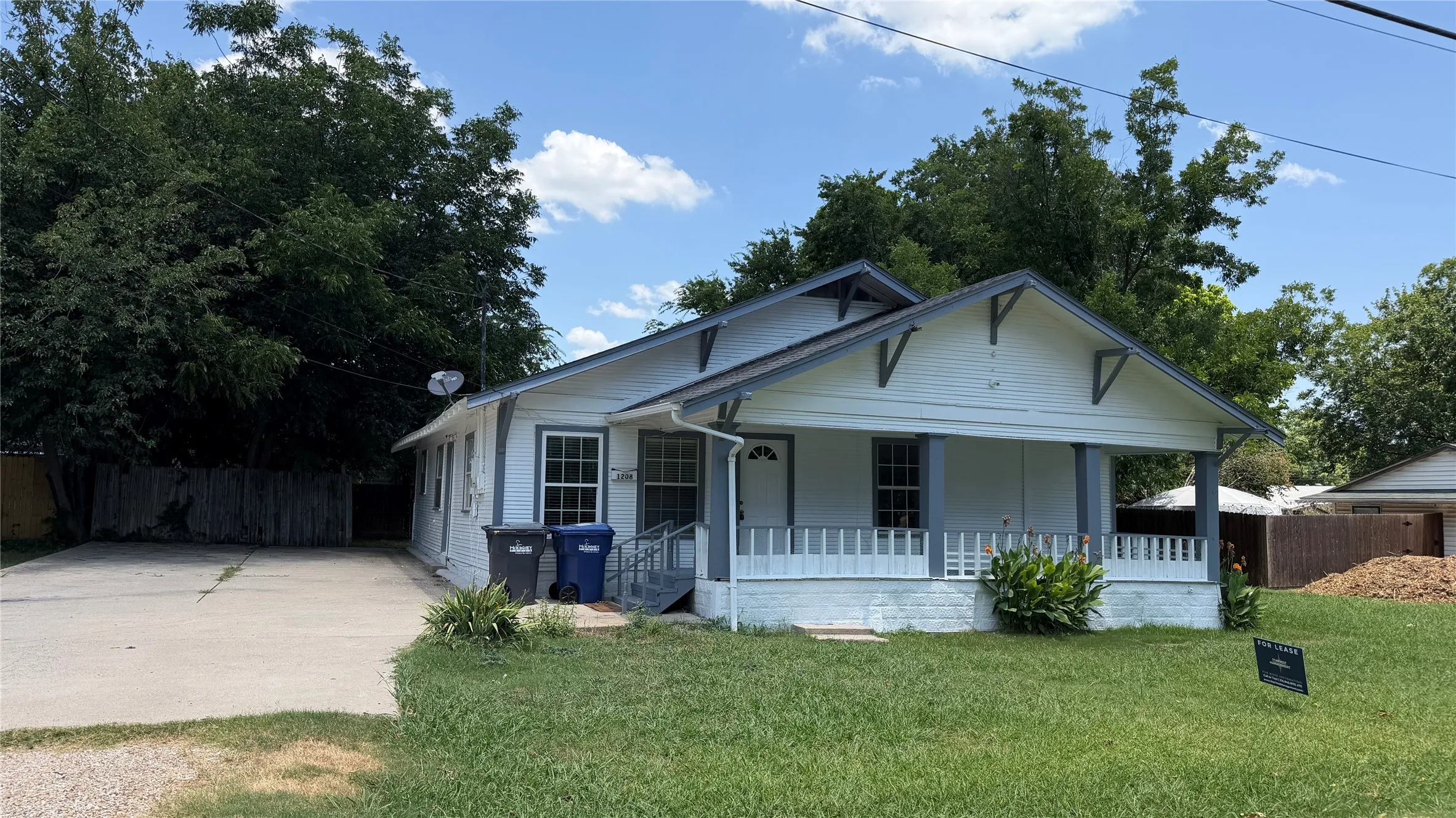 Single-story residence featuring a covered front porch with white railing, a gabled roofline, and a concrete driveway