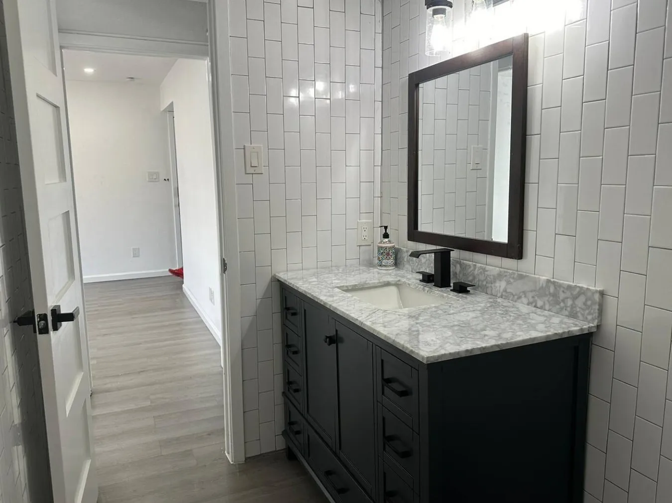 Bathroom with vanity, light wood-style flooring, and tile walls
