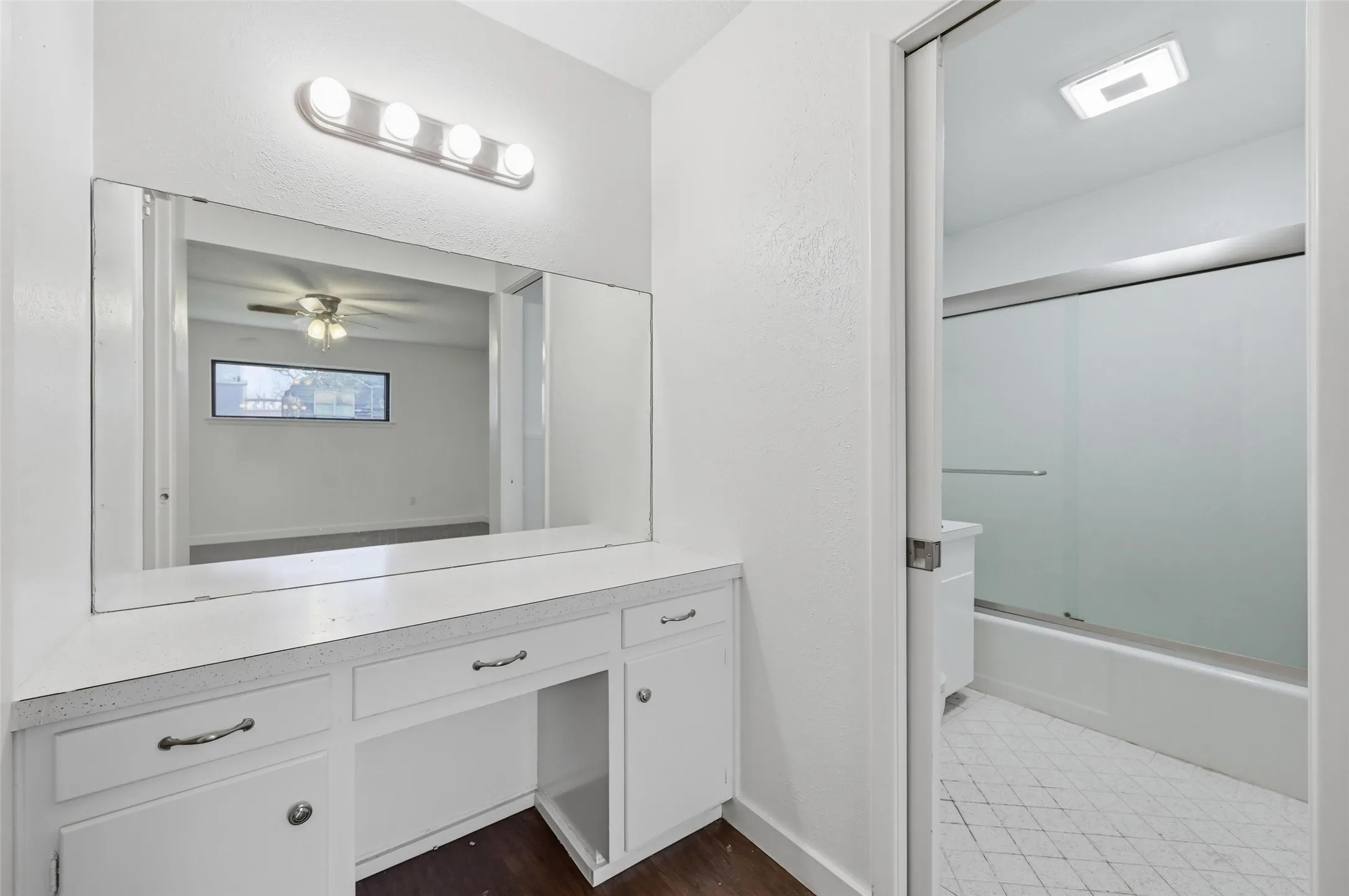 Bathroom featuring vanity, bath / shower combo with glass door, dark wood-style flooring, and a ceiling fan