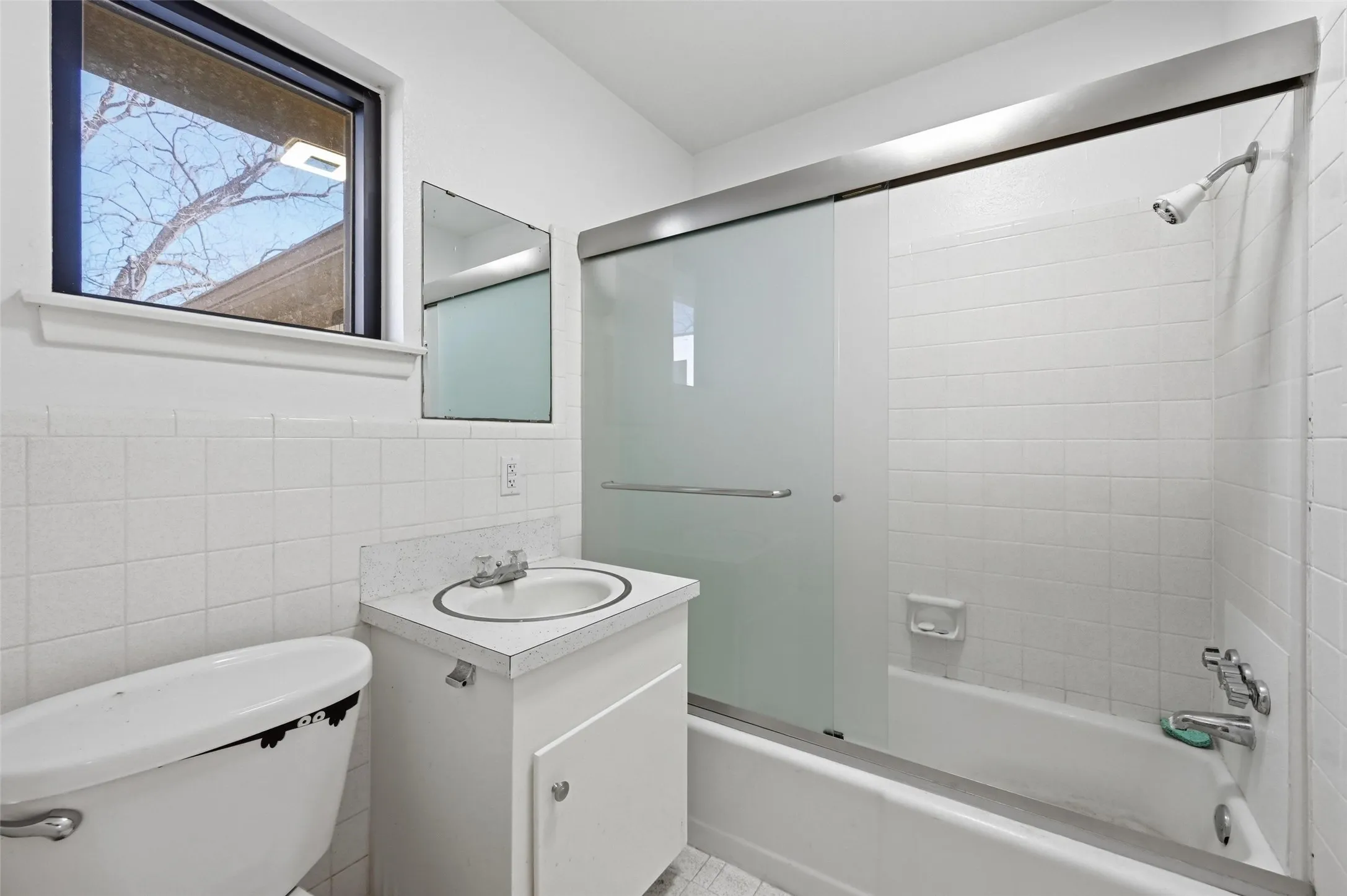 Bathroom with vanity, tile walls, and enclosed tub / shower combo