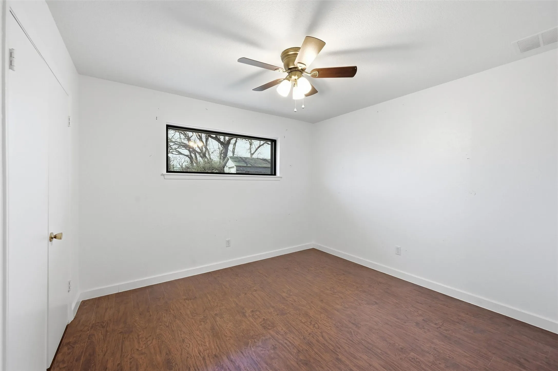 Empty room featuring dark wood-style flooring and ceiling fan