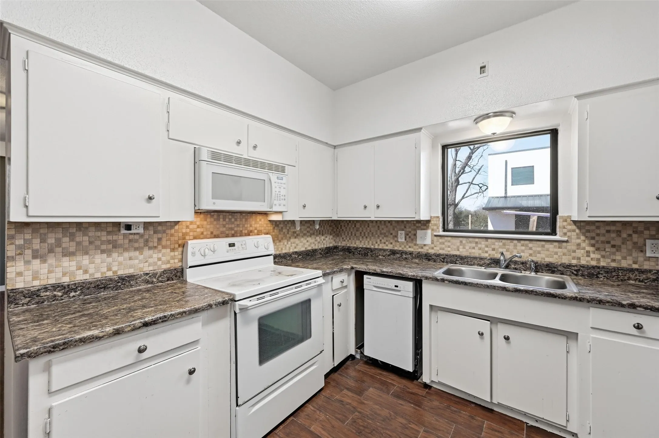 Kitchen and break area with dark countertops, white appliances, and white cabinetry