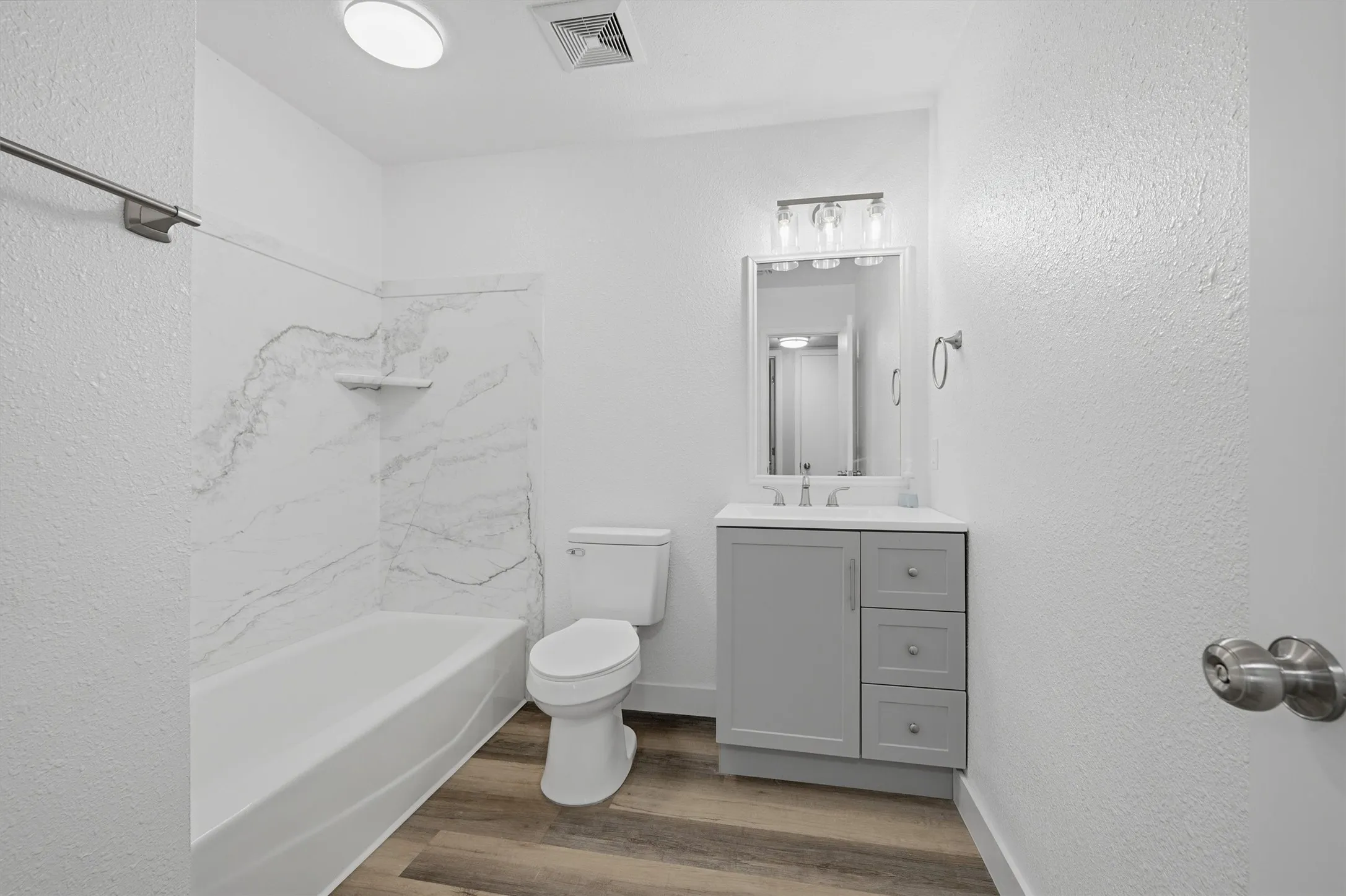 The guest bathroom has all new updates, like lighting, exhaust fan, vanity, toilet, towel bars, and tub surround