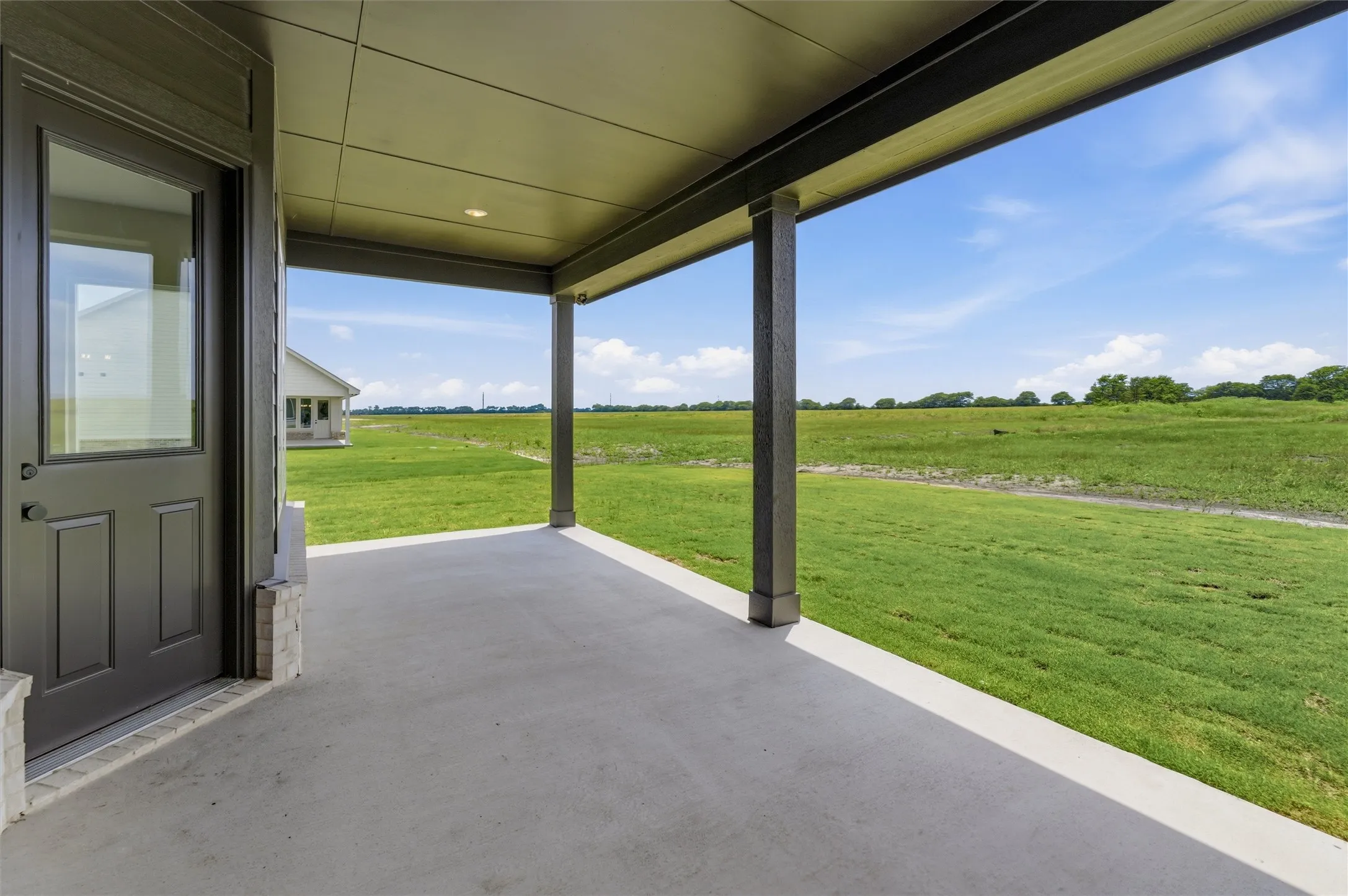 Covered patio featuring a concrete surface, overhead lighting, and dark-finished support columns