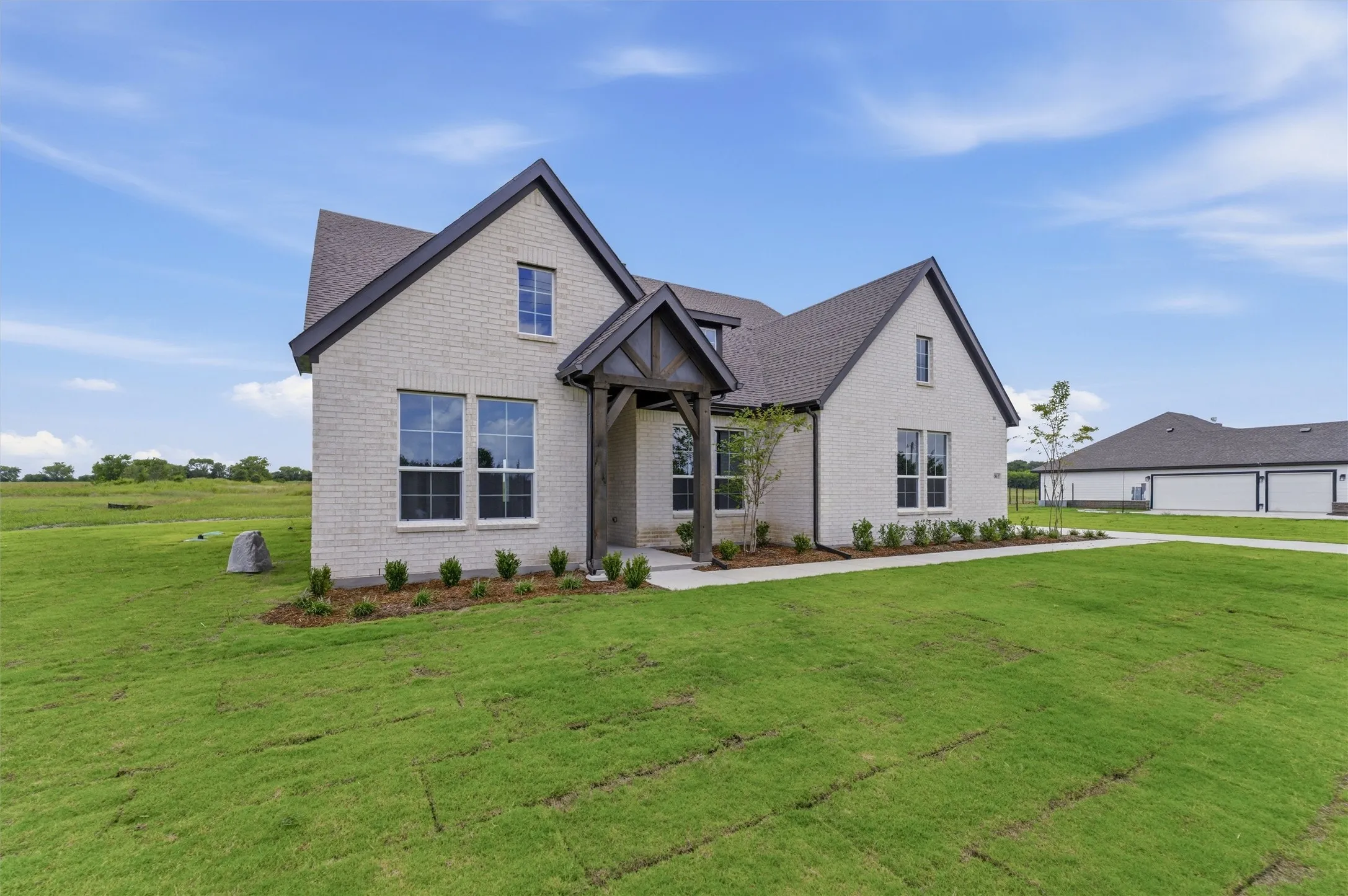 Contemporary architecture featuring light-colored brick, dark roofing, and a prominent front entrance with timber accents
