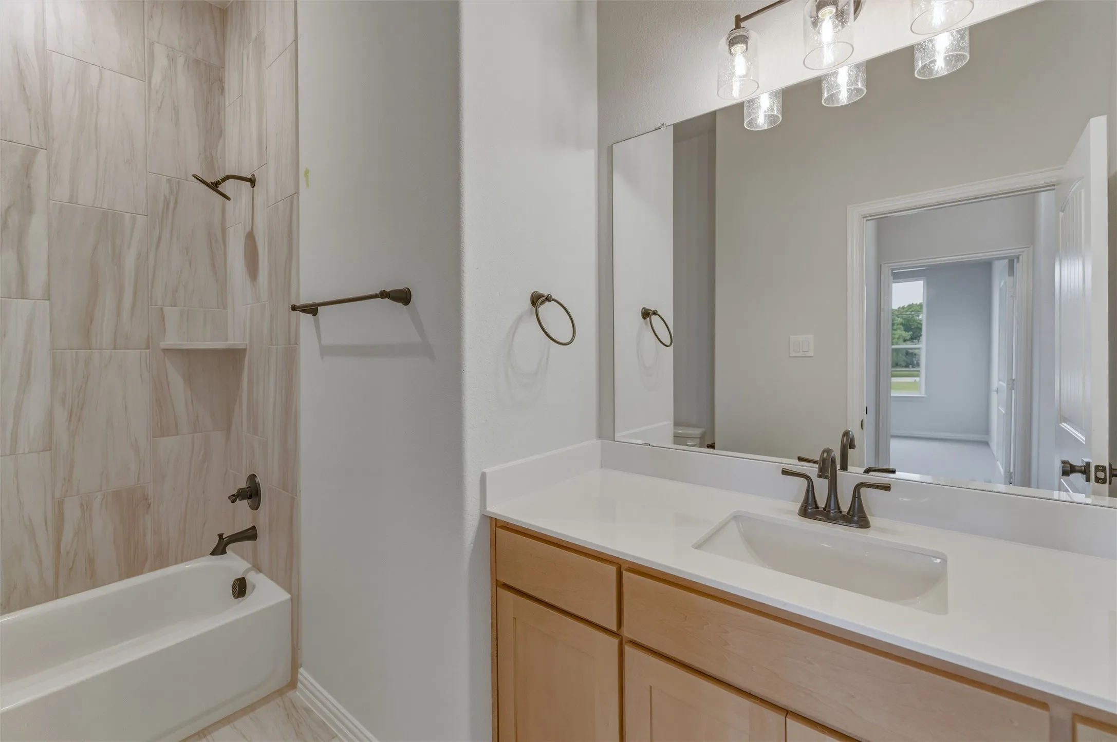 Bathroom featuring a vanity with a white countertop and an undermount sink, bronze-finish faucet, and a wall-mounted mirror