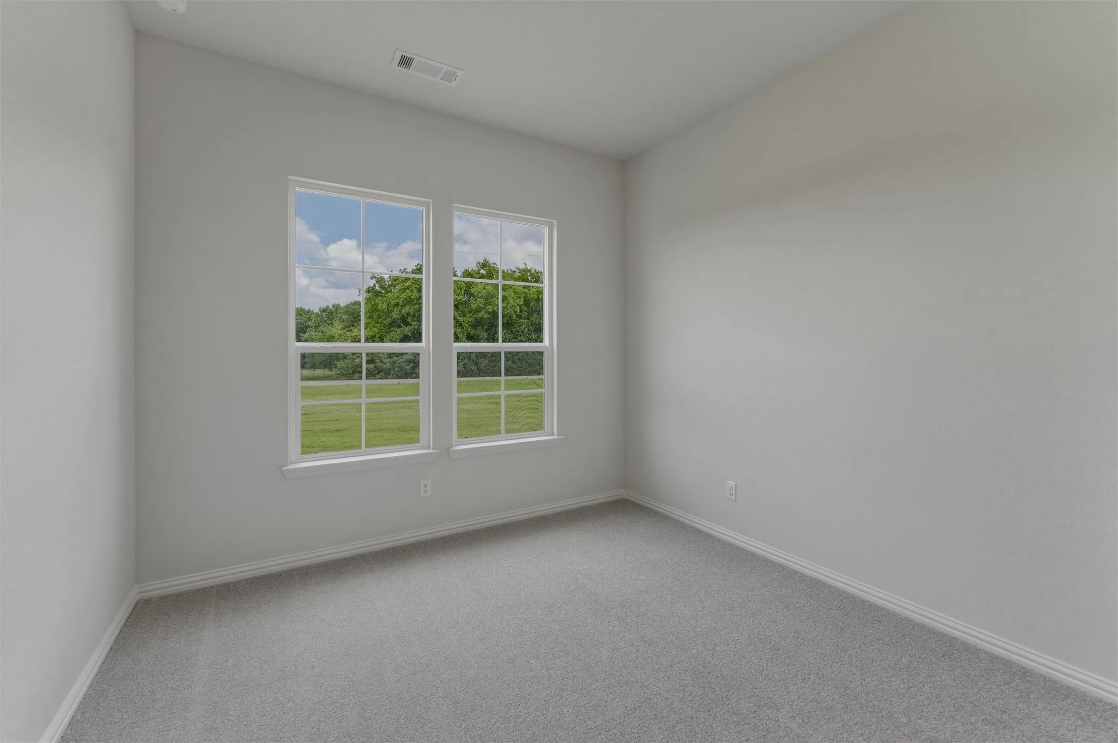 Neutral-toned room featuring a light gray wall finish, gray carpeting, and white baseboards